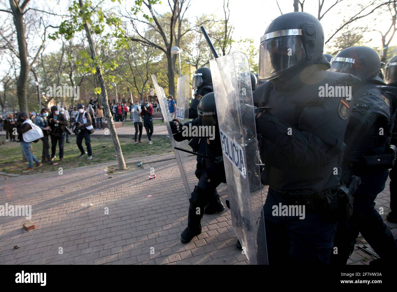 Madrid, Spagna; 07.04.2021.- la polizia riceve pietre e altri oggetti gettati da Neighbours.Vox svolge il suo primo atto di pre-campagna elettorale a Madrid nel quartiere operaio di Vallecas. La polizia nazionale si scontra con i residenti del quartiere di Madrid, che protestavano contro l'atto pre-campagna del partito di estrema destra. Il leader del partito, Santiago Abascal, ha interrotto il suo raduno e si è scontrato con diversi partecipanti alle proteste. VOX aveva riunito trecento partecipanti nella popolarmente chiamata 'Piazza Rossa' di Vallecas, separati da uno stretto cordone di polizia, i residenti del n Foto Stock