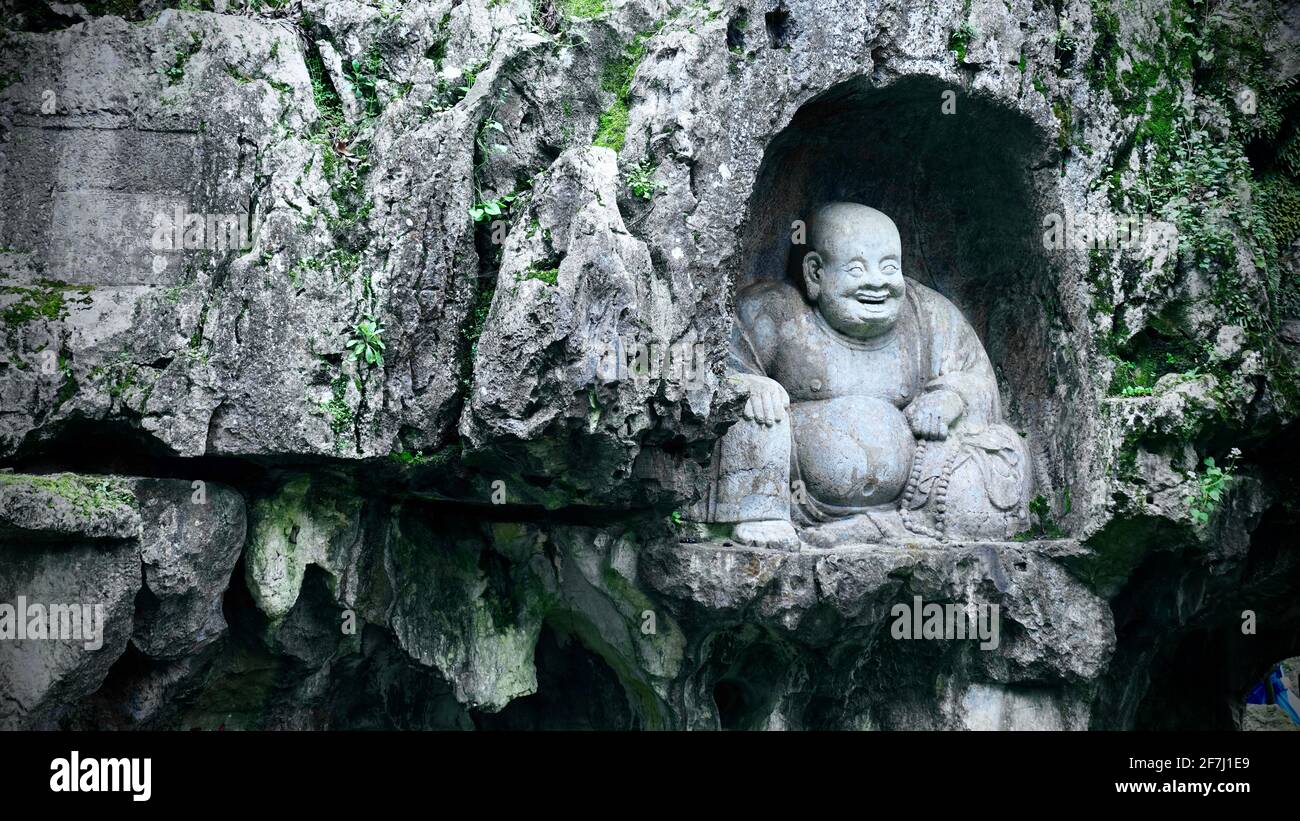 Una statua di Buddha di Maitreya scolpita in pietra su un muro di pietra nel tempio Lingyin si trova a Hangzhou, Zhejiang, Cina. Foto Stock