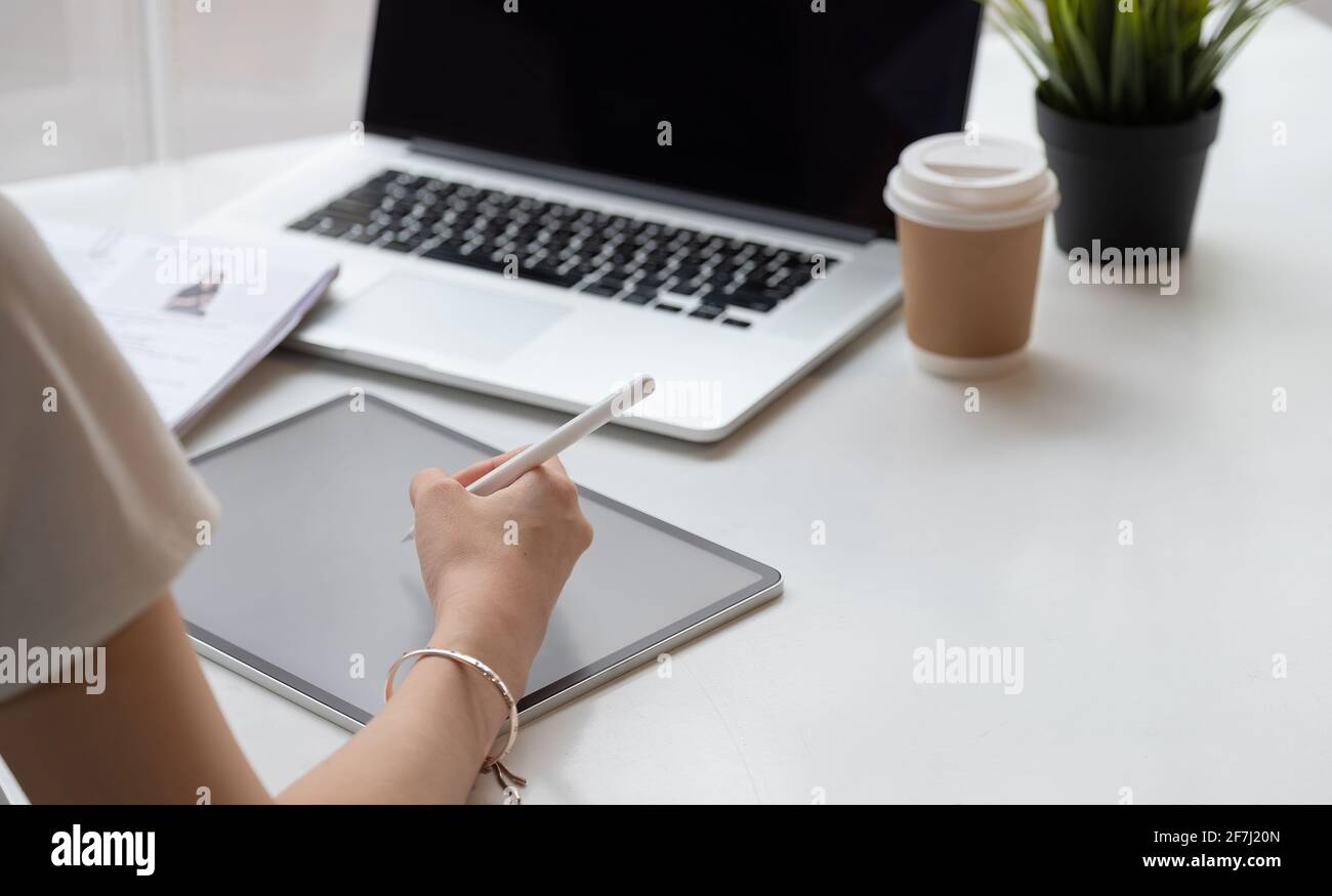 Primo piano di una donna grafica disegnatrice su di lei proietta con il teblet digitale in un ambiente di lavoro creativo moderno Foto Stock
