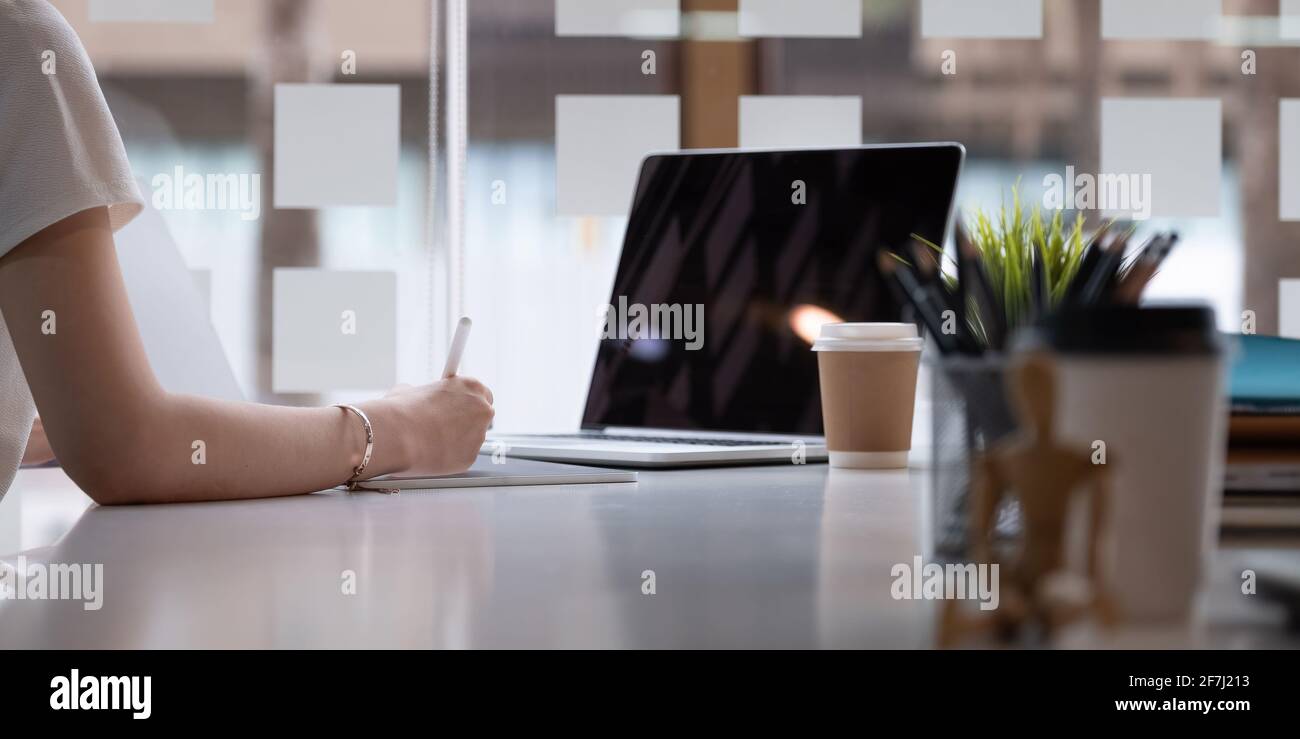 Primo piano di una donna grafica disegnatrice su di lei proietta con il teblet digitale in un ambiente di lavoro creativo moderno Foto Stock