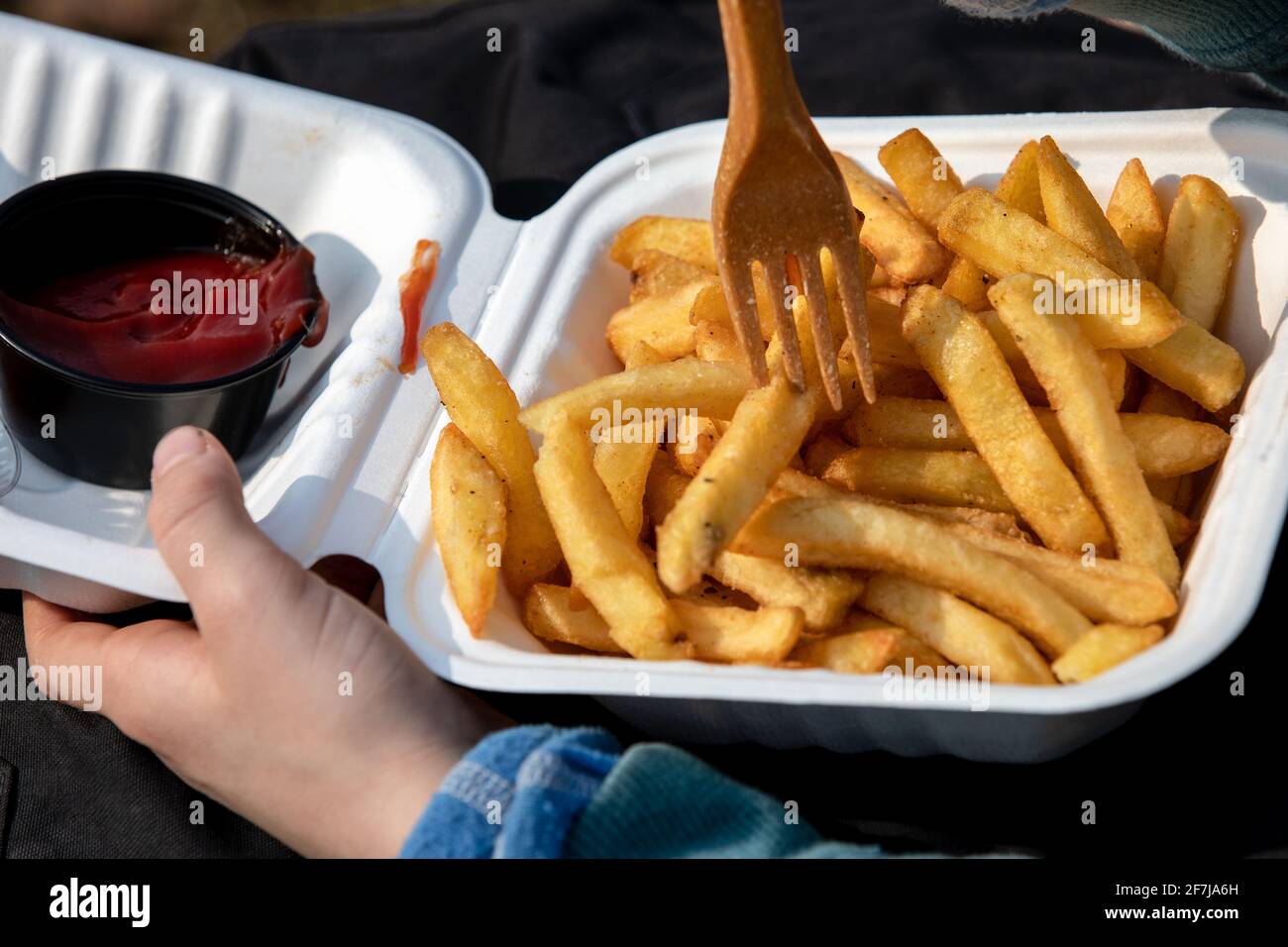 Il bambino mangia patatine fritte con ketchup o salsa di pomodoro. Cibo malsano, da asporto e ordinazioni a casa. Foto Stock