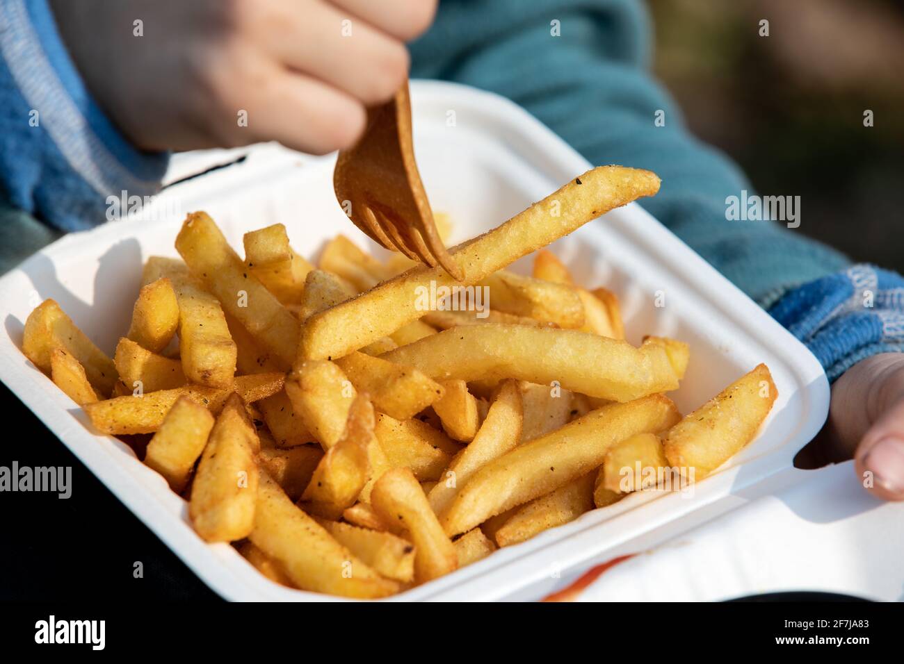 Il bambino mangia patatine fritte. Cibo malsano, da asporto e ordinazioni a casa. Foto Stock