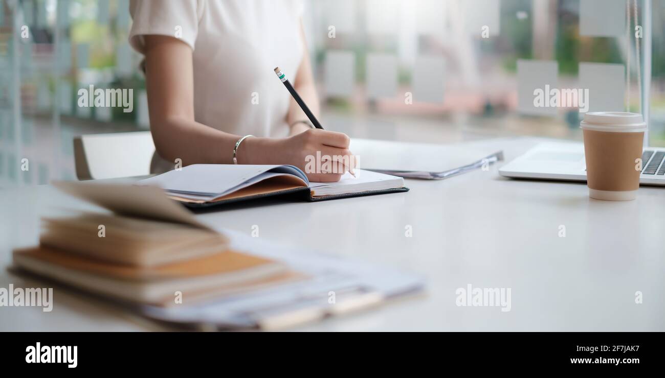 Concetto di economia finanziaria, attività bancarie e ricerca di mercato azionario. Commerciante o scrittura della matita di tenuta finanziaria al taccuino sulla scrivania. Foto Stock
