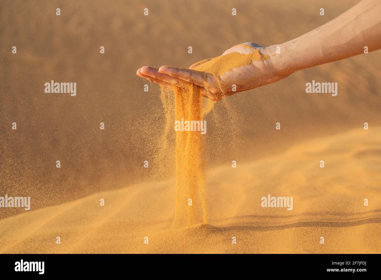 Deserto, sabbia puffs attraverso le dita di una mano mans Foto Stock
