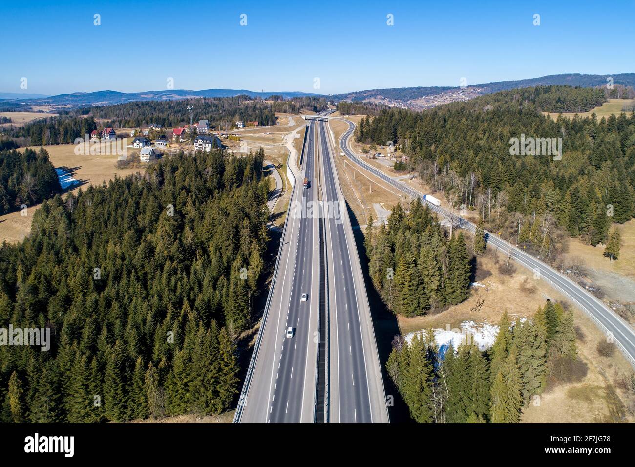 Vecchia strada e nuova autostrada da Cracovia a Zakopane in Polonia, chiamata Zakopianka con viadotti, crocevia elevato e auto. Vista aerea in inverno. Foto Stock