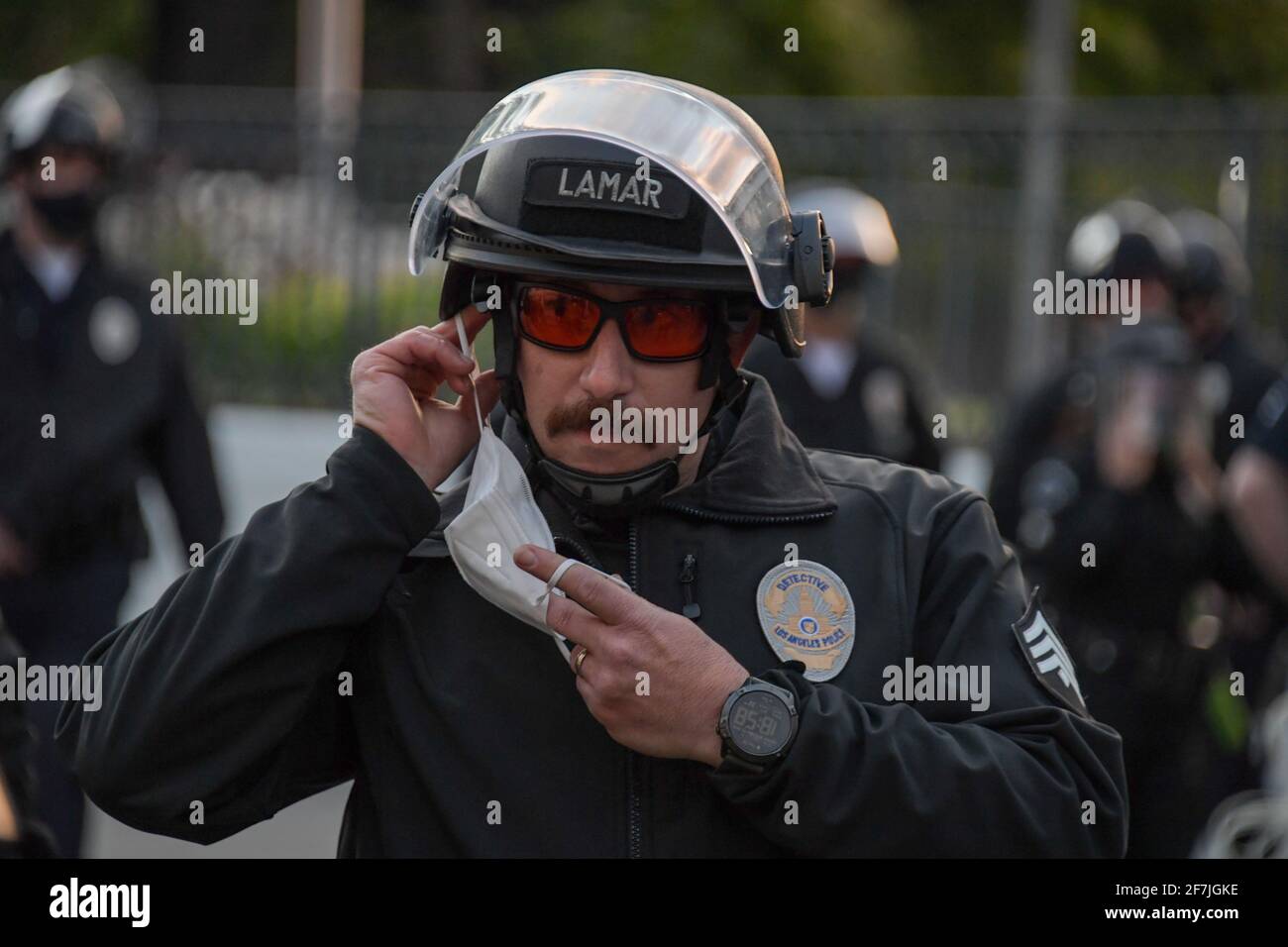 Il detective Lamar del Dipartimento di polizia di Los Angeles regola una copertura facciale mentre risponde a una protesta vicino al lago Echo Park, giovedì 25 marzo 2021 Foto Stock