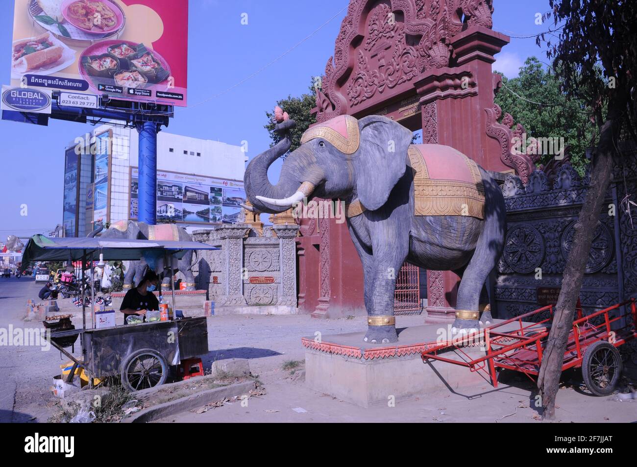 Durante un focolaio di COVID - 19, una donna cambogiana vende calamari alla griglia su un carrello di spinta al di fuori della Pagoda di Nonmonia, mentre indossa una maschera protettiva / copertura, durante la pandemia di coronavirus. Stueng Meanchey, Phnom Penh, Cambogia. © Kraig Lieb Foto Stock