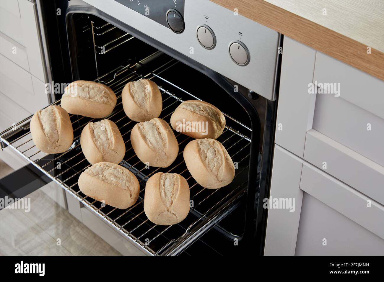 Angolo elevato di panini rotondi su scivolo in metallo griglia in forno da forno Foto Stock