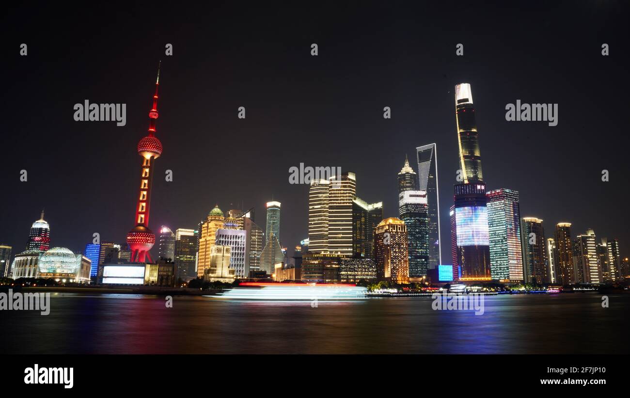 Alti edifici e torri con colorate luci a LED accese durante la notte nella città di Shanghai, in barca che attraversa il fiume. Foto Stock