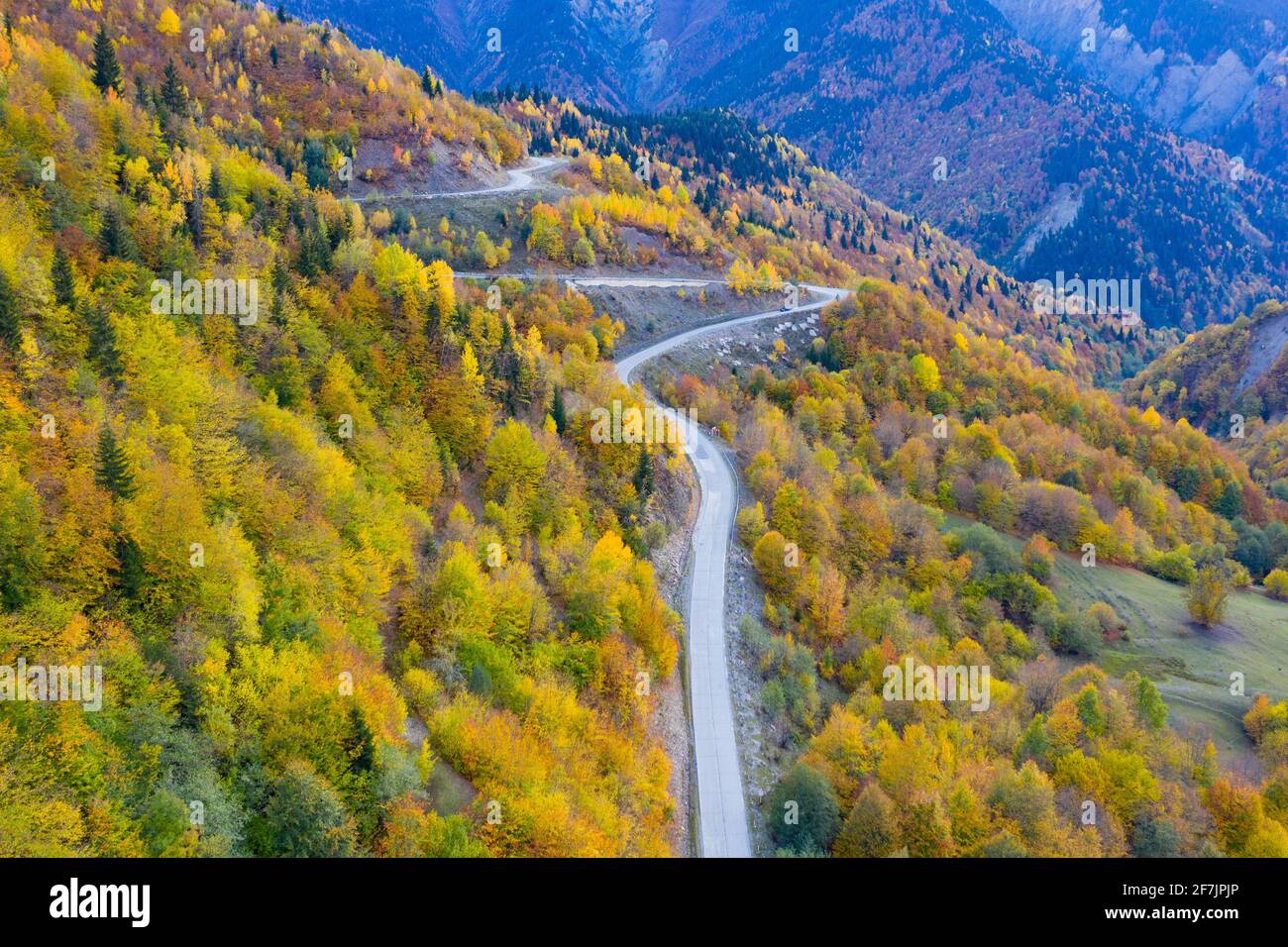 Strada tortuosa in montagna, vista della foresta d'autunno da un drone Foto Stock