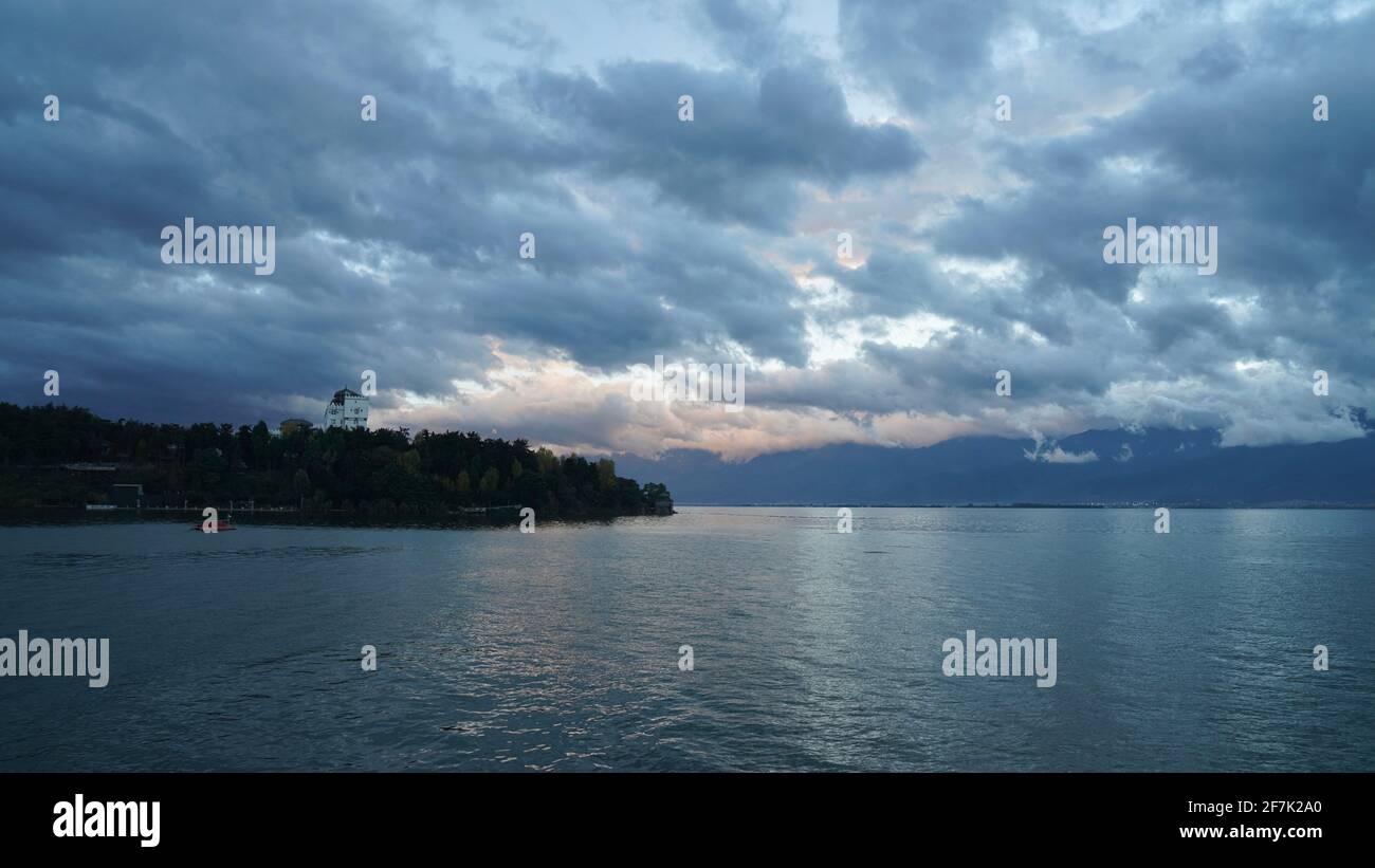 Lago di Erhai a Dali con cielo nuvoloso con cielo blu durante la notte, con un'isola lontana. Foto Stock