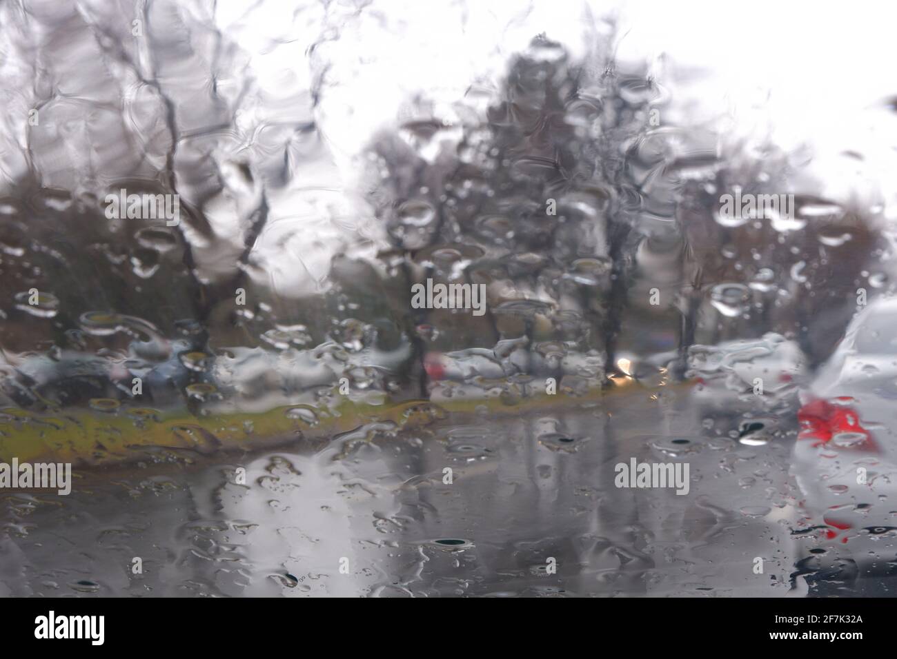 Gocce d'acqua sulla finestra in un giorno piovoso, strade bagnate Foto Stock