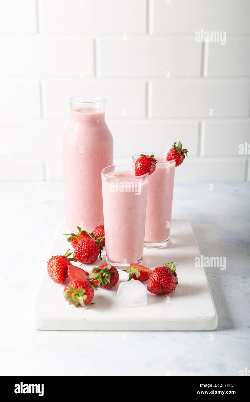 Frullato fresco di fragole fresche fatte in casa con cubetti di ghiaccio e fragole fresche su sfondo bianco. Foto Stock
