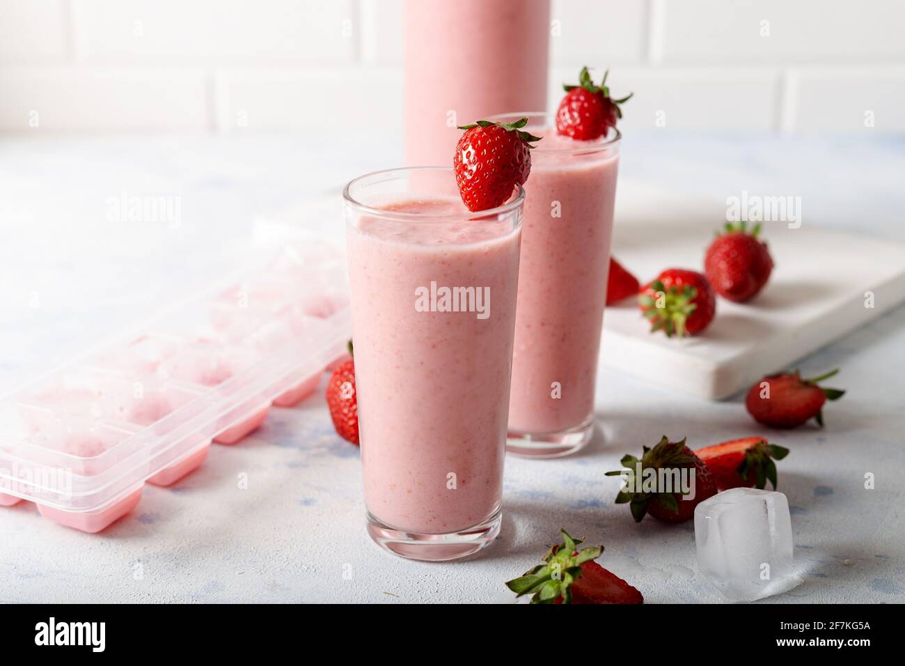 Frullato fresco di fragole fresche fatte in casa con cubetti di ghiaccio e fragole fresche su sfondo bianco. Foto Stock