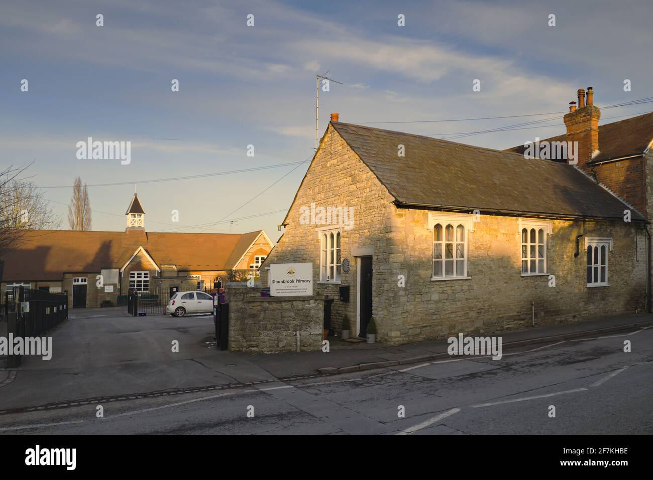 Sharnbrook High Street, Bedfordshire, Inghilterra, Regno Unito, nel tardo pomeriggio - gli edifici vittoriani della scuola elementare del villaggio di Sharnbrook Foto Stock