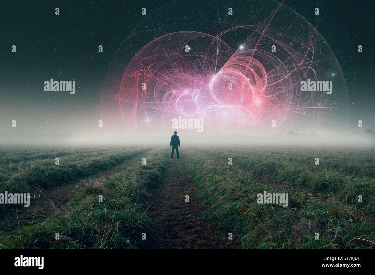Un uomo in piedi in un campo atmosferico nebbioso di notte guardando su una struttura di fantascienza aliena nel cielo. Foto Stock