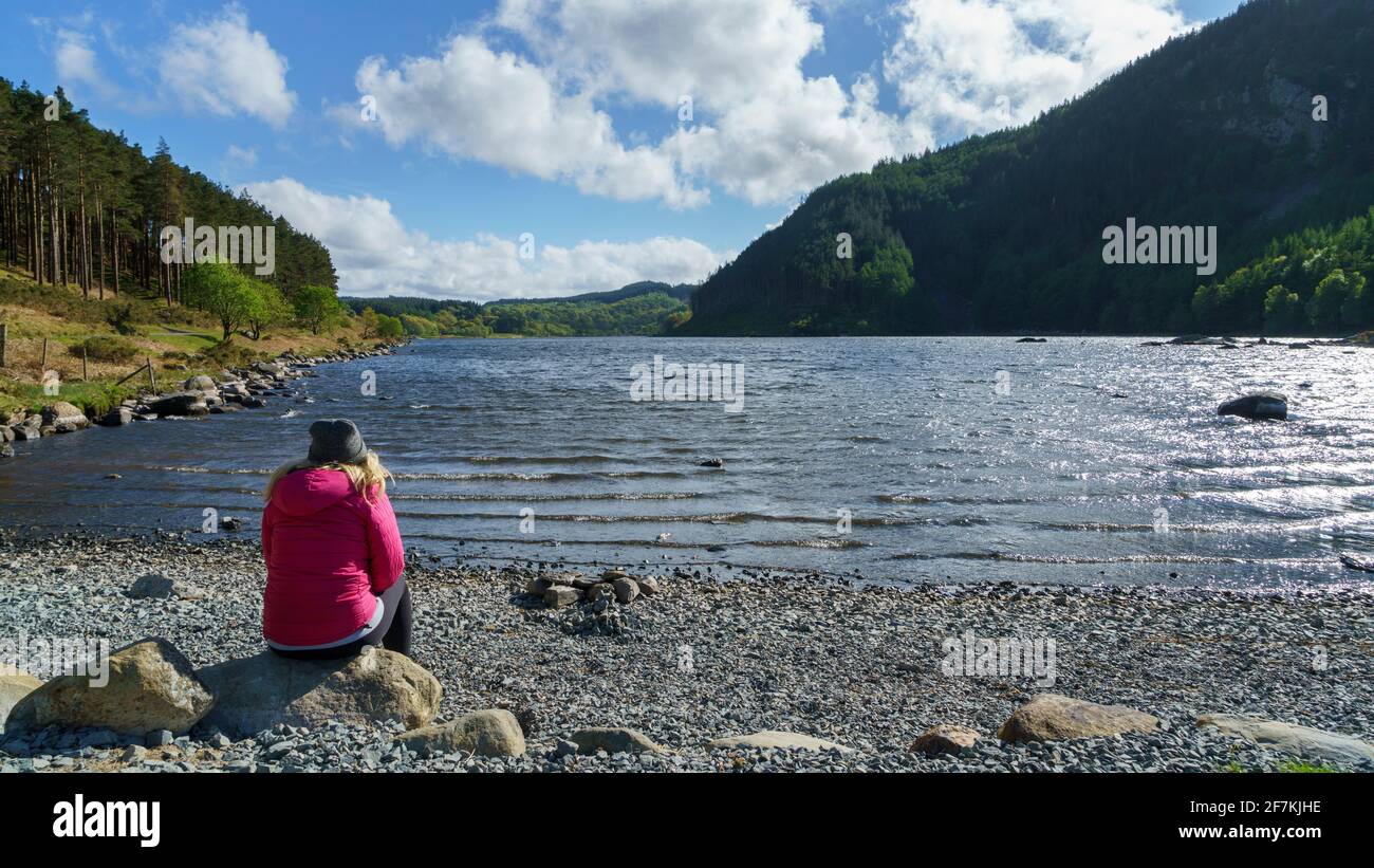 Giovane donna che si affaccia su un lago in Snowdonia National Parco nel Galles Foto Stock