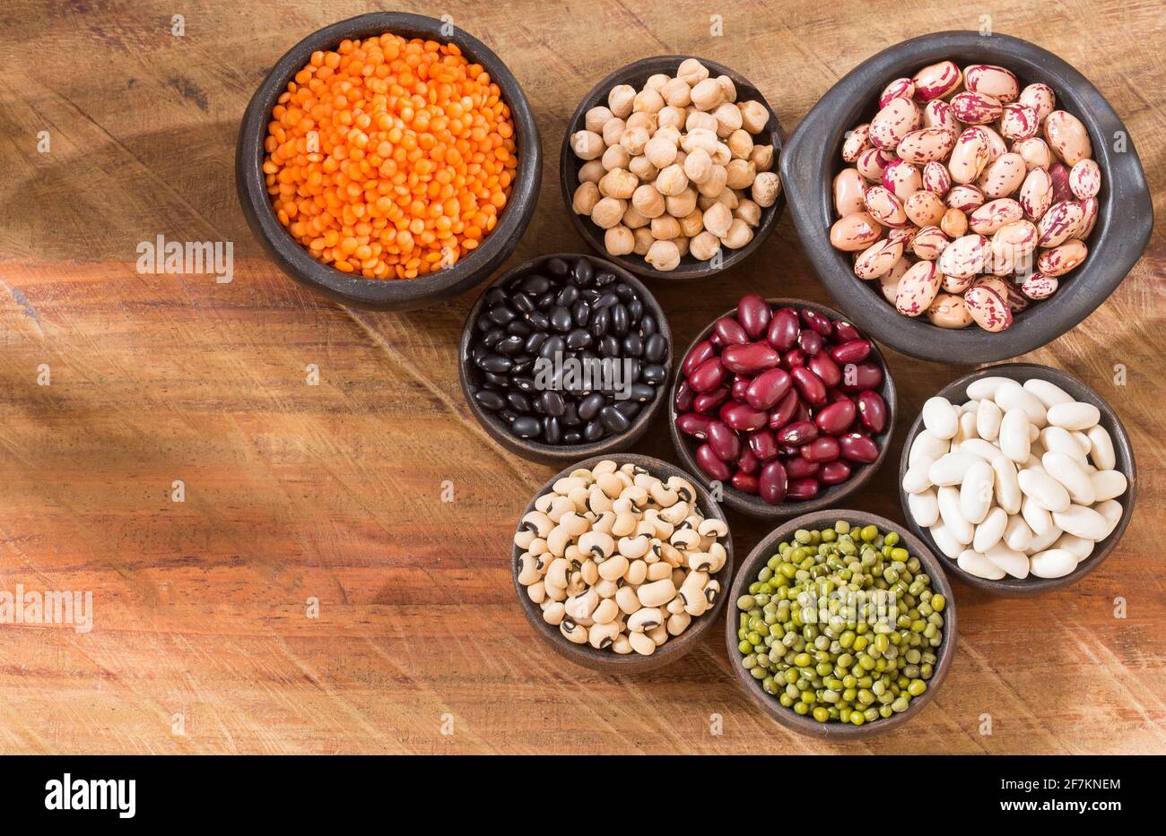 Varietà di grani - pinto, nero, mungo, bianco, lenticchie e ceci su fondo di legno Foto Stock