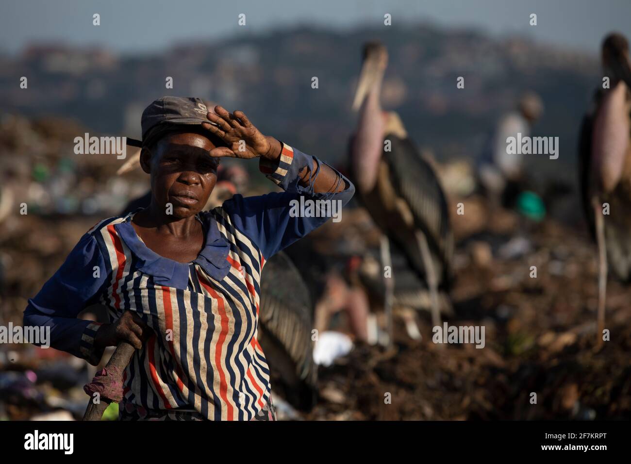KAMPALA, UGANDA: Una donna prende uno sfiatatoio. IMMAGINI che mostrano lavoratori ugandesi esausti vagliando attraverso tonnellate di rifiuti in discarica in cerca di re Foto Stock