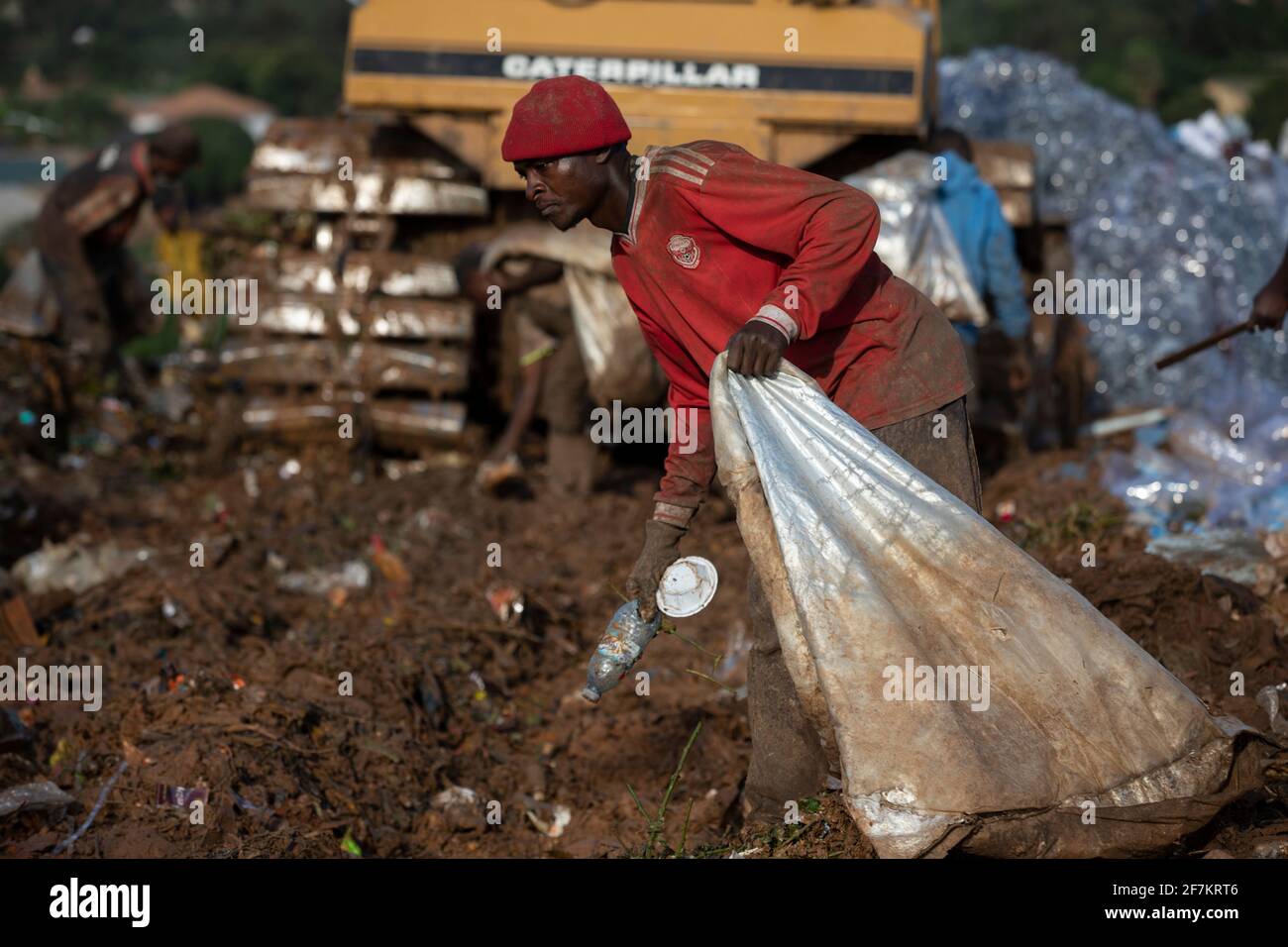 KAMPALA, UGANDA: Un operaio vana attraverso i rifiuti. IMMAGINI che mostrano lavoratori ugandesi esausti che vagliano tonnellate di rifiuti in discarica in se Foto Stock