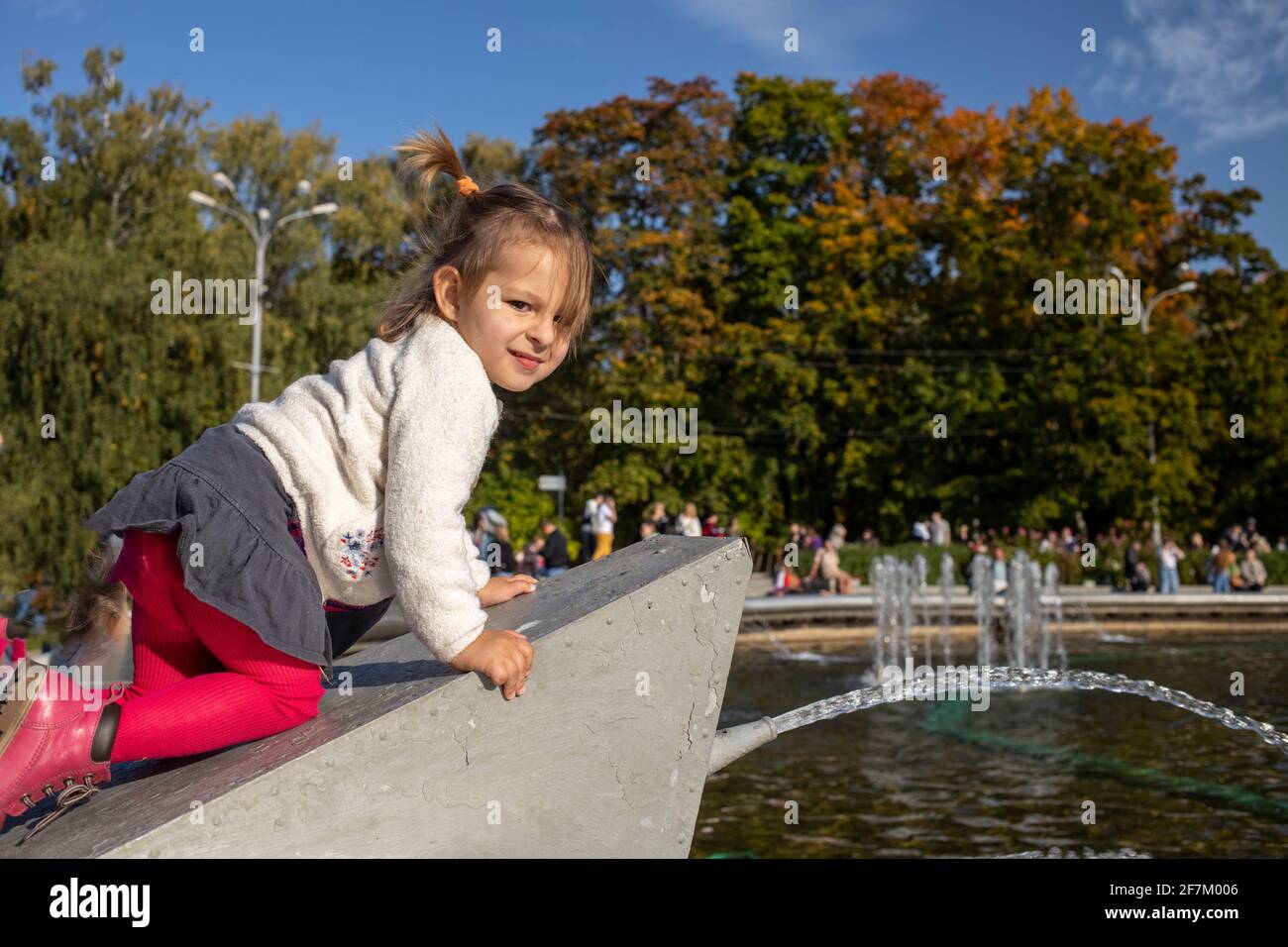 adorabile bambino sale la fontana nel parco. weekend a piedi con i bambini nel parco in buone condizioni meteorologiche Foto Stock