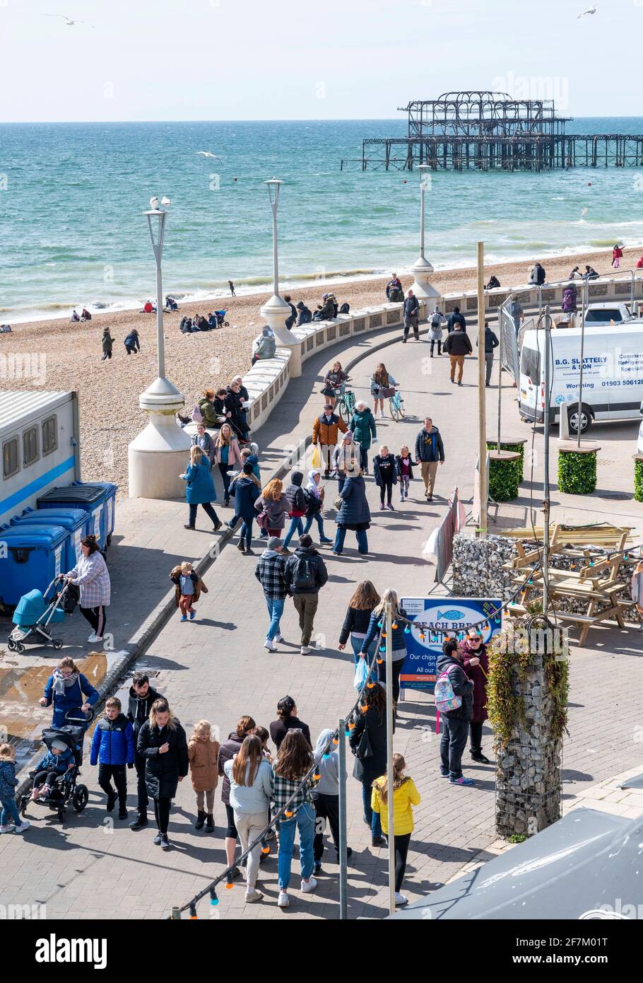 Brighton UK 8 aprile 2021 - i visitatori possono godersi una passeggiata lungo il lungomare di Brighton in una bella giornata soleggiata ma fredda sulla costa meridionale . Dal lunedì le restrizioni di blocco sono ulteriormente attenuate in Inghilterra con bar e ristoranti che sono autorizzati a servire in ambienti esterni: Credit Simon Dack / Alamy Live News Foto Stock