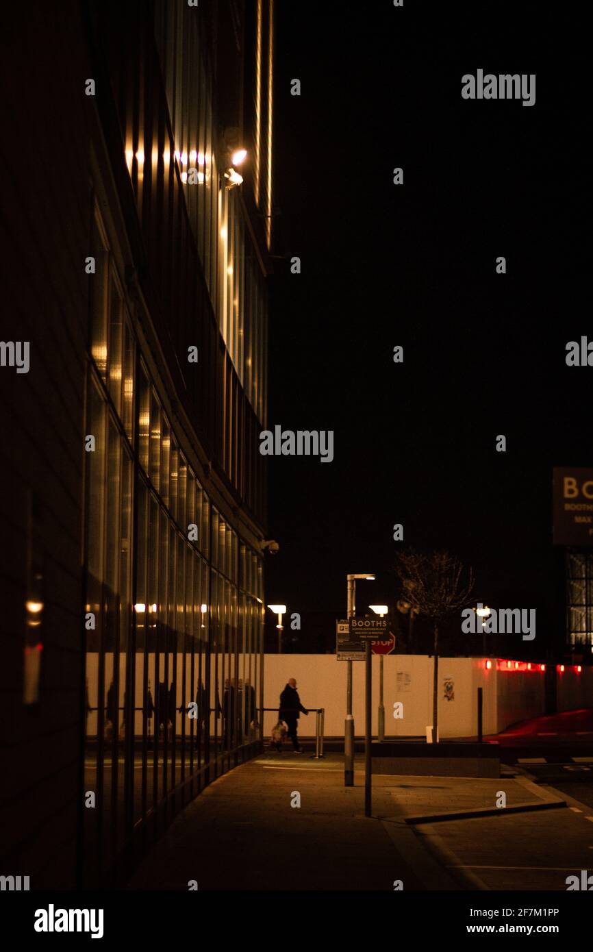 Silhouette di una persona che cammina nel buio attraverso Media City, Salford Foto Stock