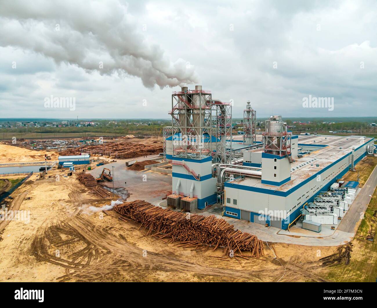 Segheria per legno di pino con macchinari per la lavorazione del legno. Impianto di lavorazione del legno. Inquinamento dell'aria dalla segheria. Fumo nell'atmosfera. Vista dall'alto, antenna Foto Stock