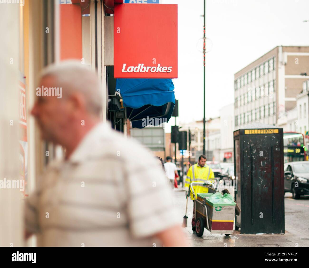 Giocatore irriconoscibile, uomo di mezza età che cammina in un negozio di scommesse Ladbrokes. Scommesse sportive, gioco d'azzardo stile di vita. Camden High St, Londra, Regno Unito. Ago 2015 Foto Stock