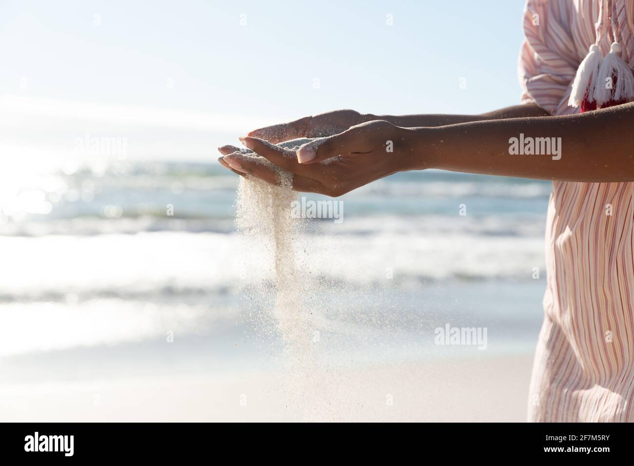 Misto razza donna sulla spiaggia vacanza versando sabbia Foto Stock