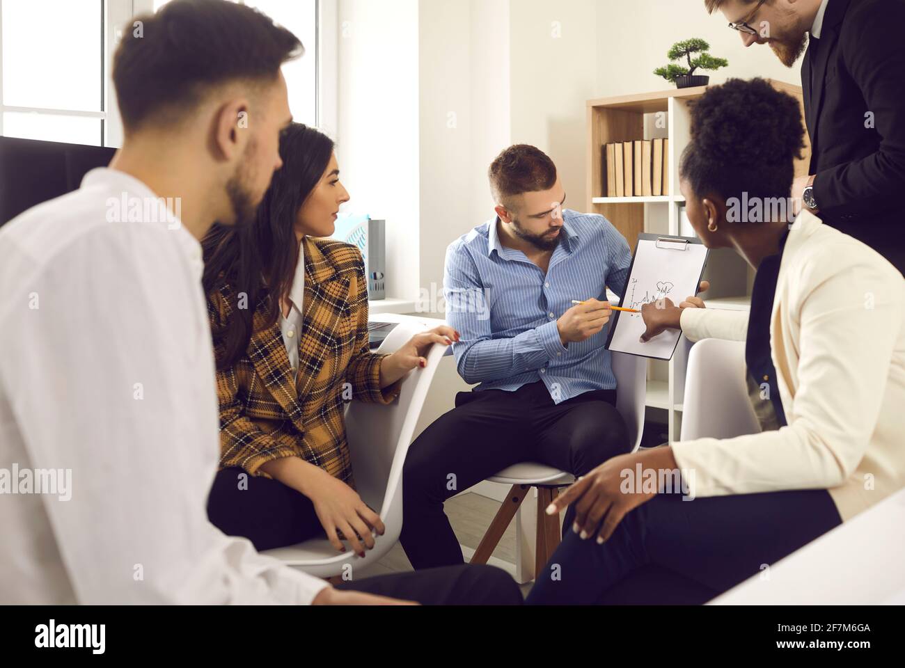 Imprenditore che spiega il piano di affari a team multiculturale specializzato in ufficio Foto Stock