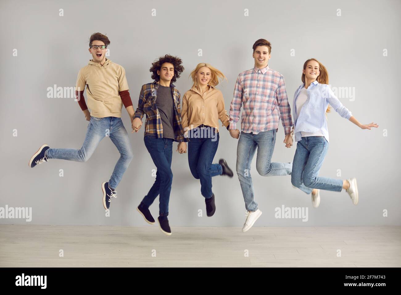 Felice adolescente studenti compagni di classe gruppo jumping full length studio ritratto Foto Stock