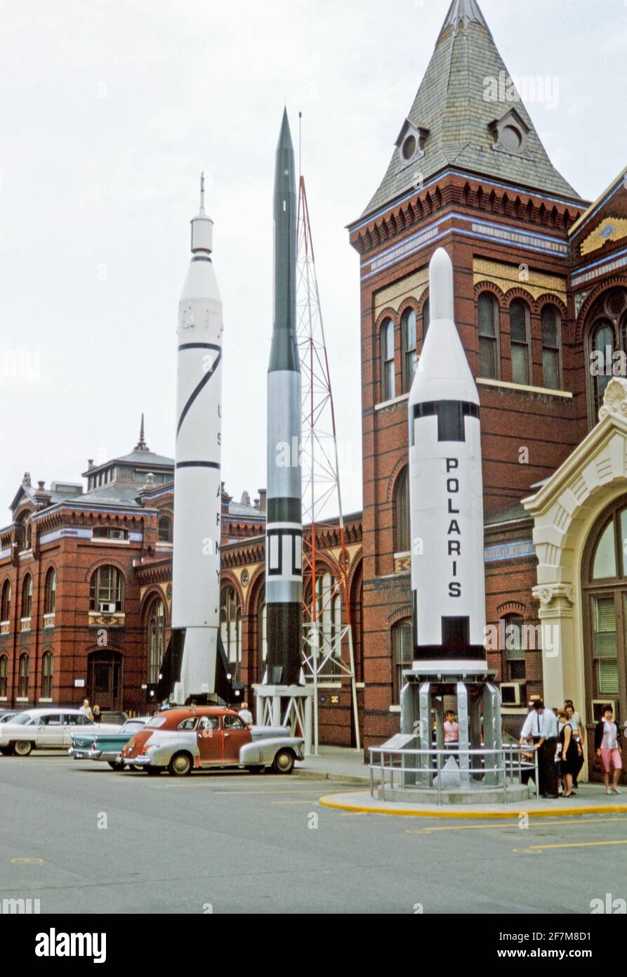 ‘Rocket Row’ lungo il lato ovest del Palazzo delle Arti e delle Industrie (prima della costruzione del National Air and Space Museum), Washington DC, USA nel 1964. I quattro missili sono il Jupiter C, che ha lanciato Explorer i, il primo satellite statunitense (a sinistra), il Vanguard (al centro) e il Polaris A-1, il primo sottomarino statunitense lanciato ICBM (a destra). Le auto sono parcheggiate nel parcheggio. Il Museo dell'aria e dello spazio fu originariamente chiamato Museo Nazionale dell'aria quando fu fondato nel 1946. Questa immagine è tratta da un vecchio lucido a colori americano amatoriale Kodak – una fotografia d'epoca degli anni '60. Foto Stock