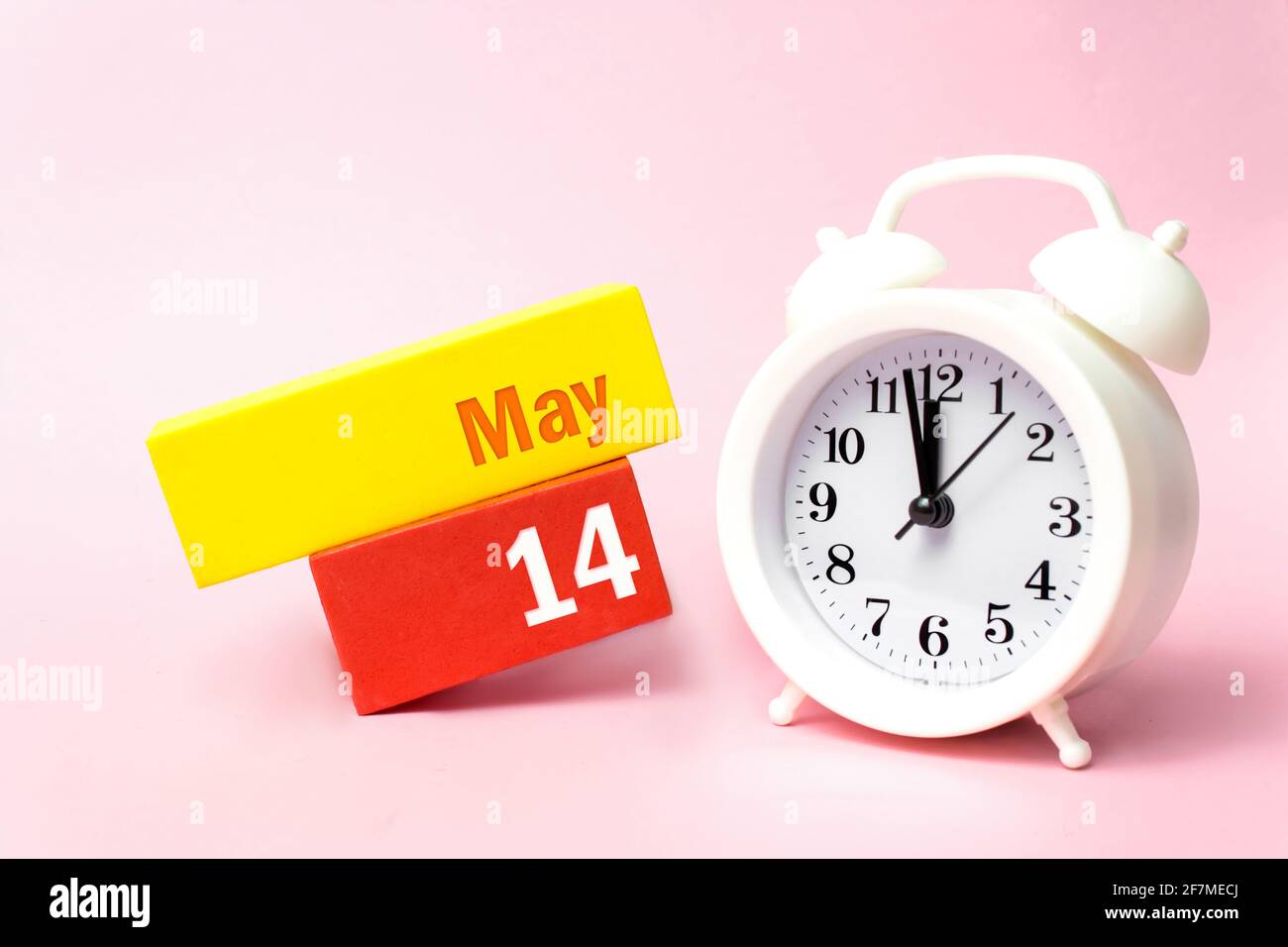 14 maggio. Giorno 14 del mese, data del calendario. Sveglia bianca su sfondo rosa pastello. Concetto di mese di primavera, giorno dell'anno Foto Stock
