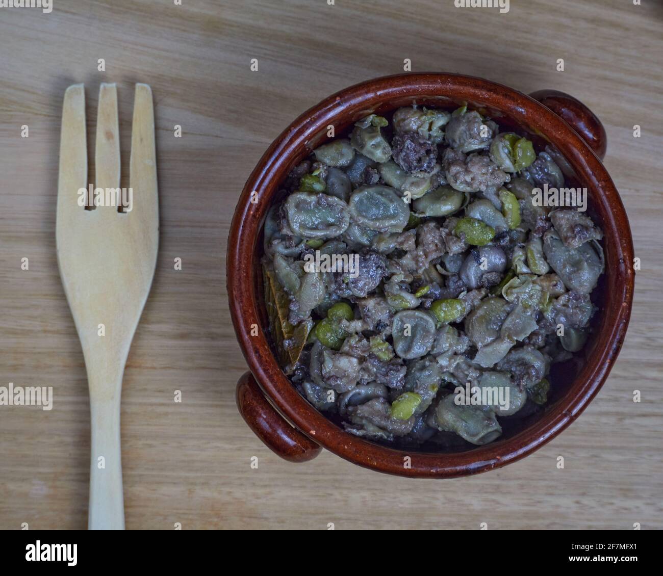 Habas a la Catalana, stufato di fagioli in una ciotola di argilla con una forchetta di legno. Vista dall'alto Foto Stock