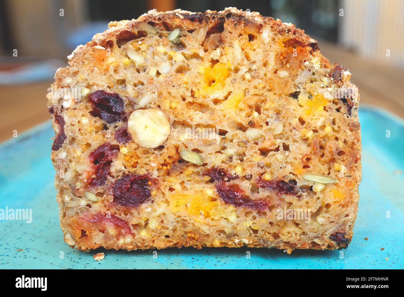 Un pezzo di pane con frutta secca su piatto blu, albicocche secche, uvetta, prugne e nocciole, vista dall'alto. Foto Stock
