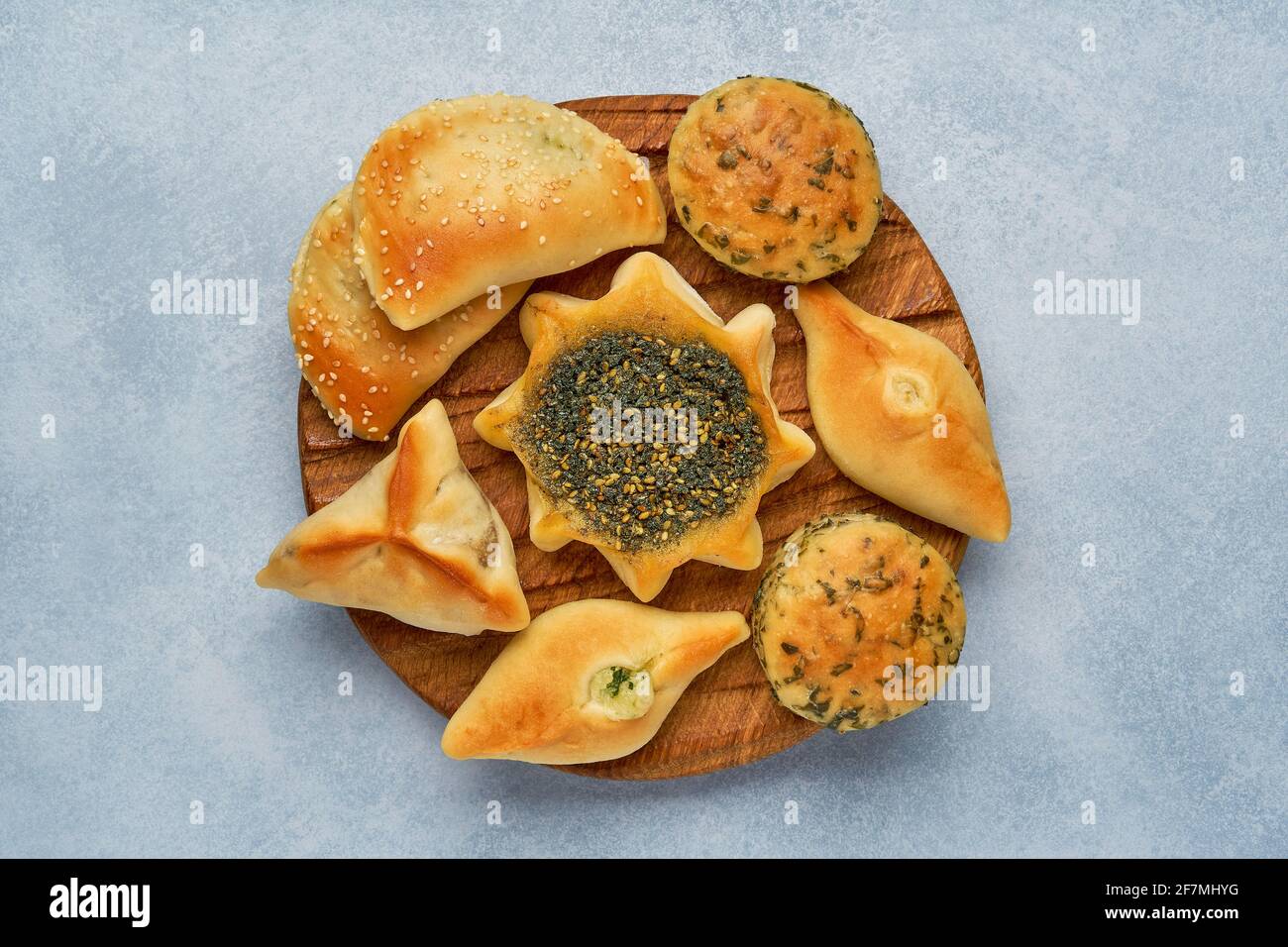 Pasticceria, fatayer o samosa, manaqeesh con zaatar e formaggio. Dolci assortiti con spinaci e patate su tavola di legno. Vista dall'alto Foto Stock