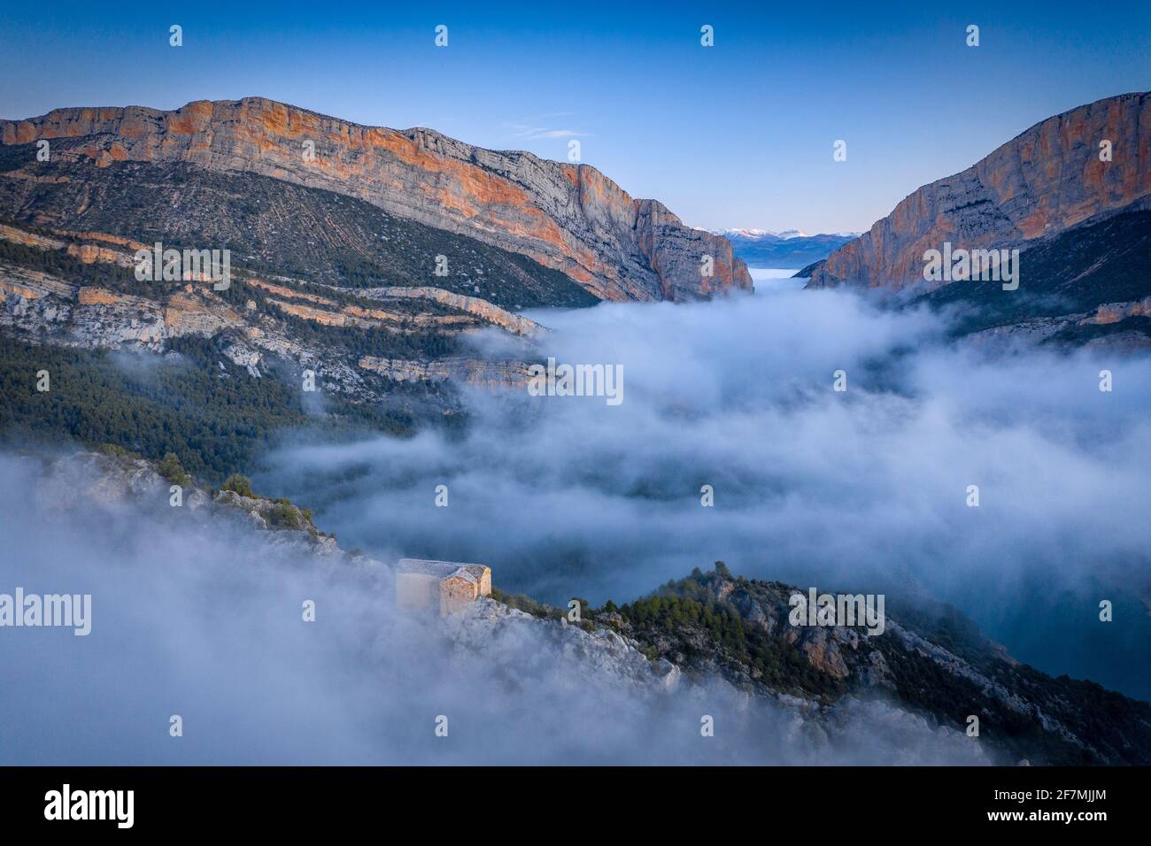 La gola del Congost de Mont-rebei e l'eremo di Santa Quiteria si affacciano in un'alba in nebbia d'inverno (Montfalcón, Aragona, Spagna, Pirenei) Foto Stock