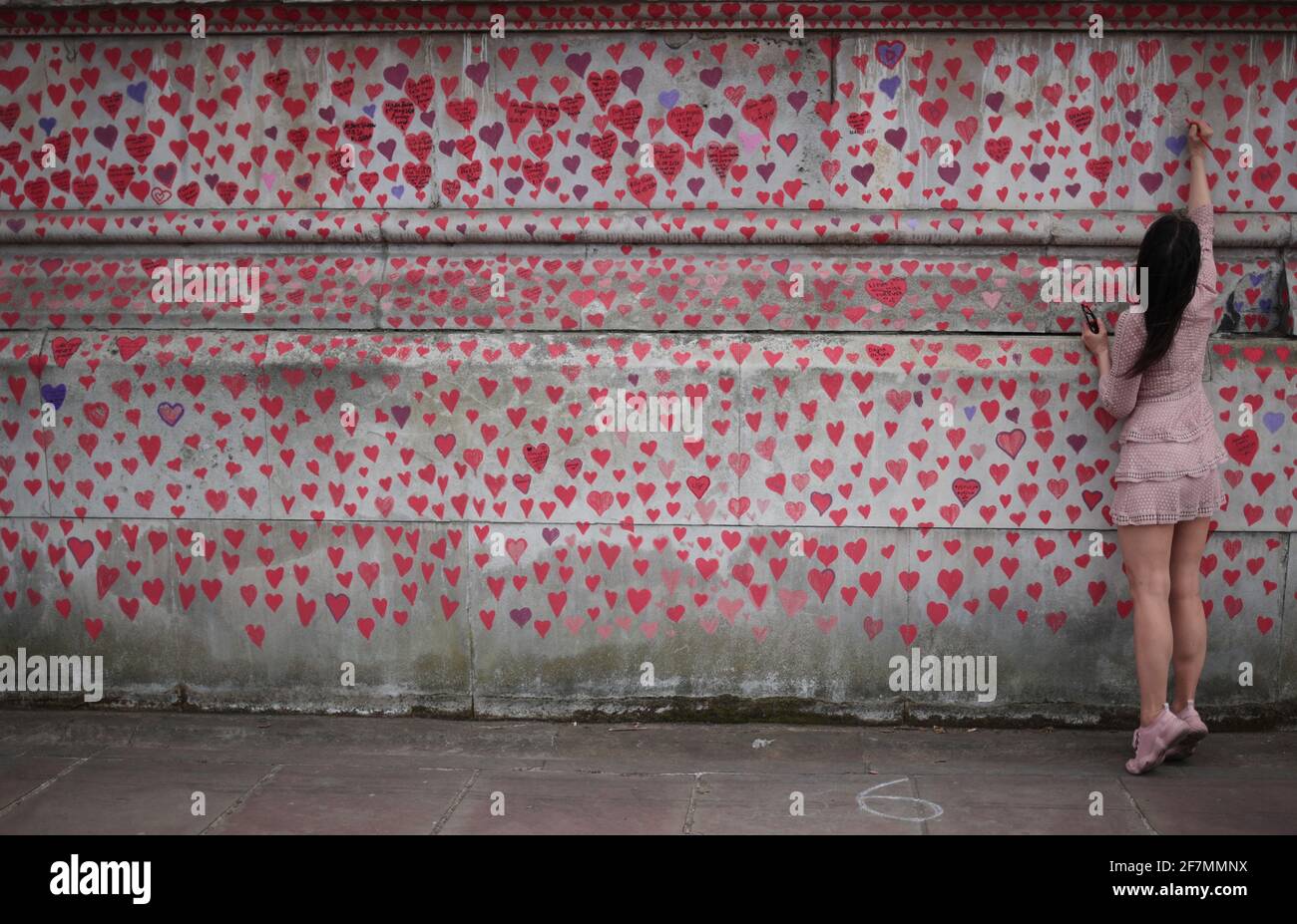 Una persona scrive un messaggio sul National Covid Memorial Wall accanto al St Thomas' Hospital, ambientato come monumento a tutti coloro che sono morti finora nel Regno Unito a causa della malattia del coronavirus (COVID-19), a Londra, Gran Bretagna, l'8 aprile 2021. REUTERS/Hannah McKay Foto Stock