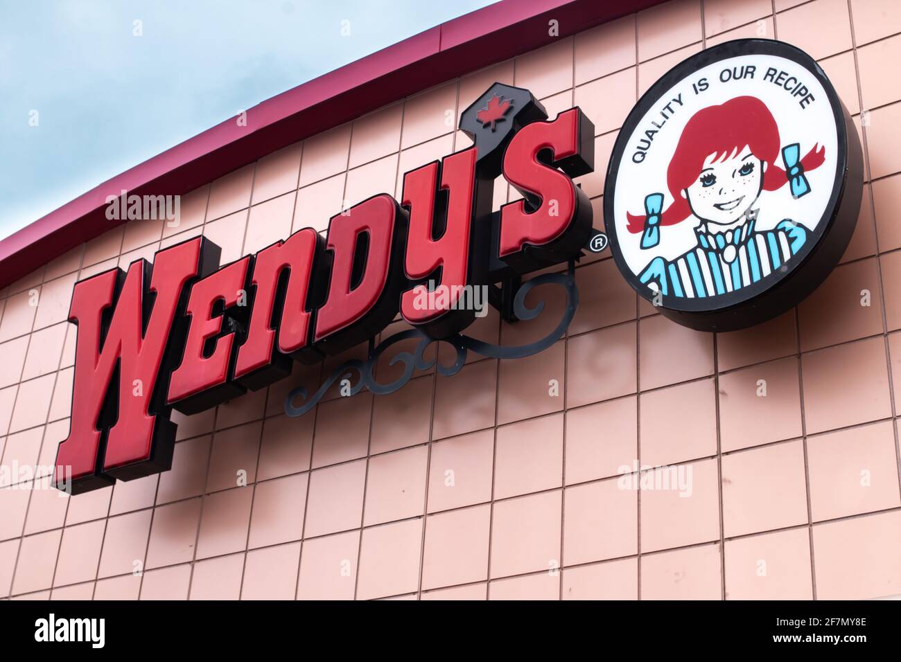 Londra Ontario, Canada - Febbraio 15 2021: Wendy's Canada franchising su una mattina blu d'inverno, girato dalla vista della strada con la foglia d'acero canadese. Foto Stock