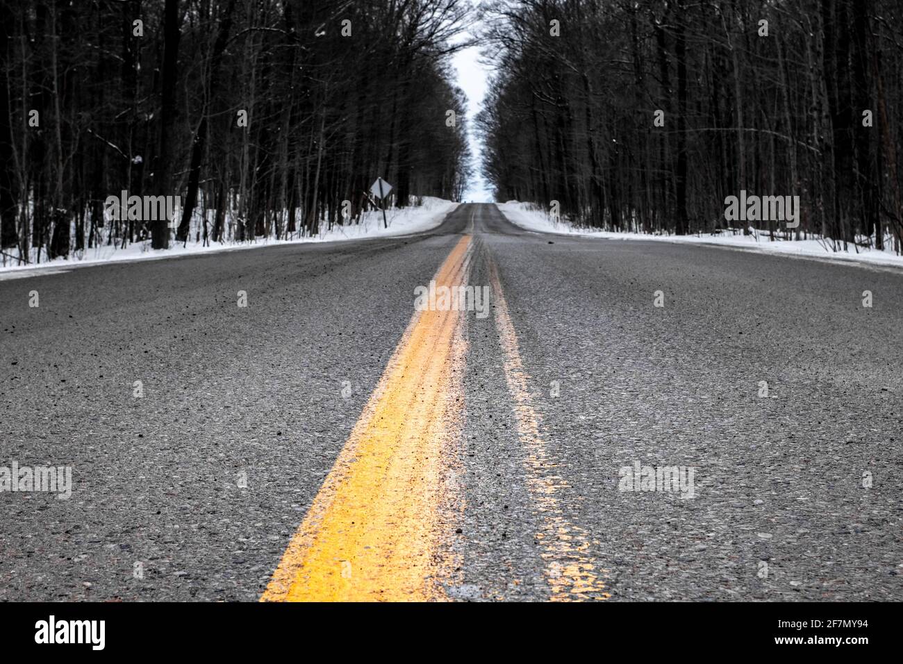 Closeup della linea gialla su una strada asfaltata nella contea di Middlesex, in un grigio giorno d'inverno canadese nel 2021. Foto Stock