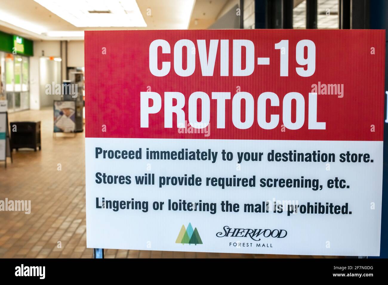 Londra, Ontario, Canada - Febbraio 28 2021: Un cartello rosso e bianco COVID-19 all'entrata del Centro commerciale Sherwood Forest. Procedere verso la destinazione. Foto Stock