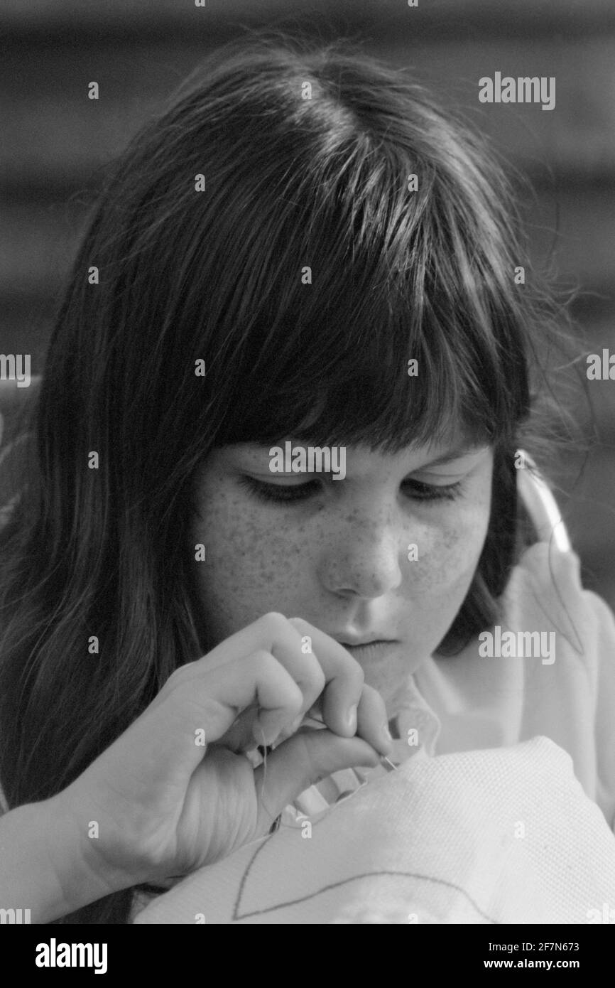 giovane ragazza che si concentra su cucire nel giardino early80 uk Foto Stock