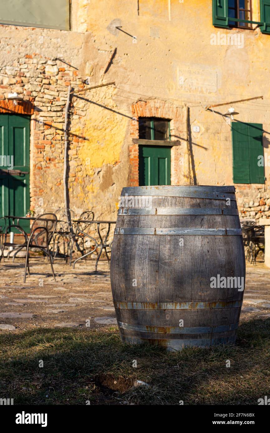 Tradizionale botte di vino in legno, tipica casa rustica in pietra italiana sullo sfondo. Spazio di copia Foto Stock