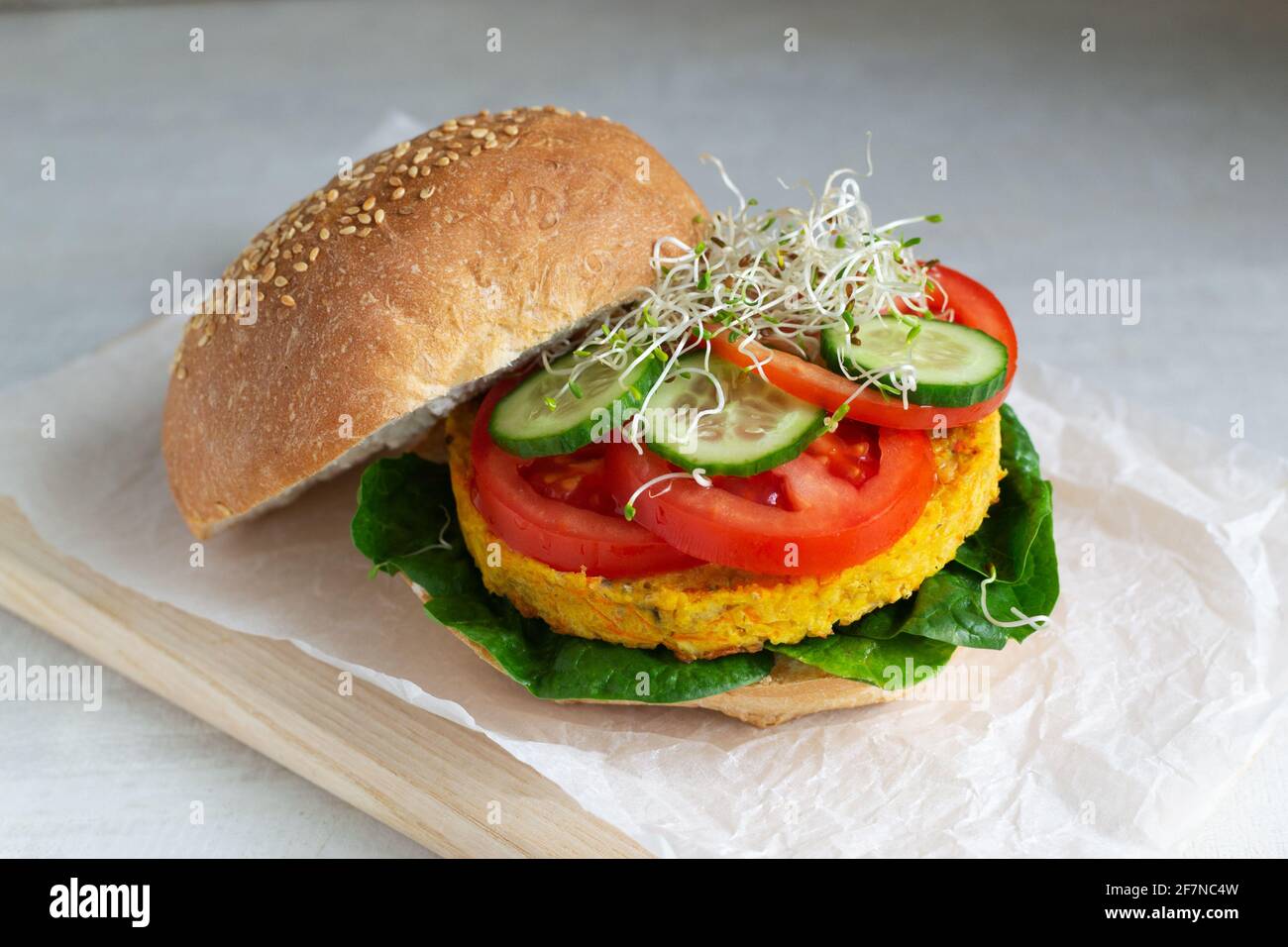 Hamburger vegetariano con cotoletta di ceci con pomodoro, cetriolo, spinaci e microsverde. Concetto di cibo vegetariano. Orientamento orizzontale. Foto Stock