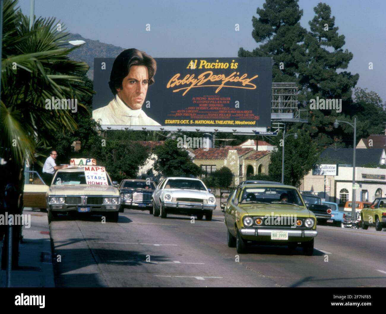 Al Pacino su cartellone per il film Bobby Deerfield sulla Sunset Strip a Los Angeles, CA con un uomo che vende mappe alle case delle stelle dal suo vagone della stazione parcheggiata, circa 1977 Foto Stock