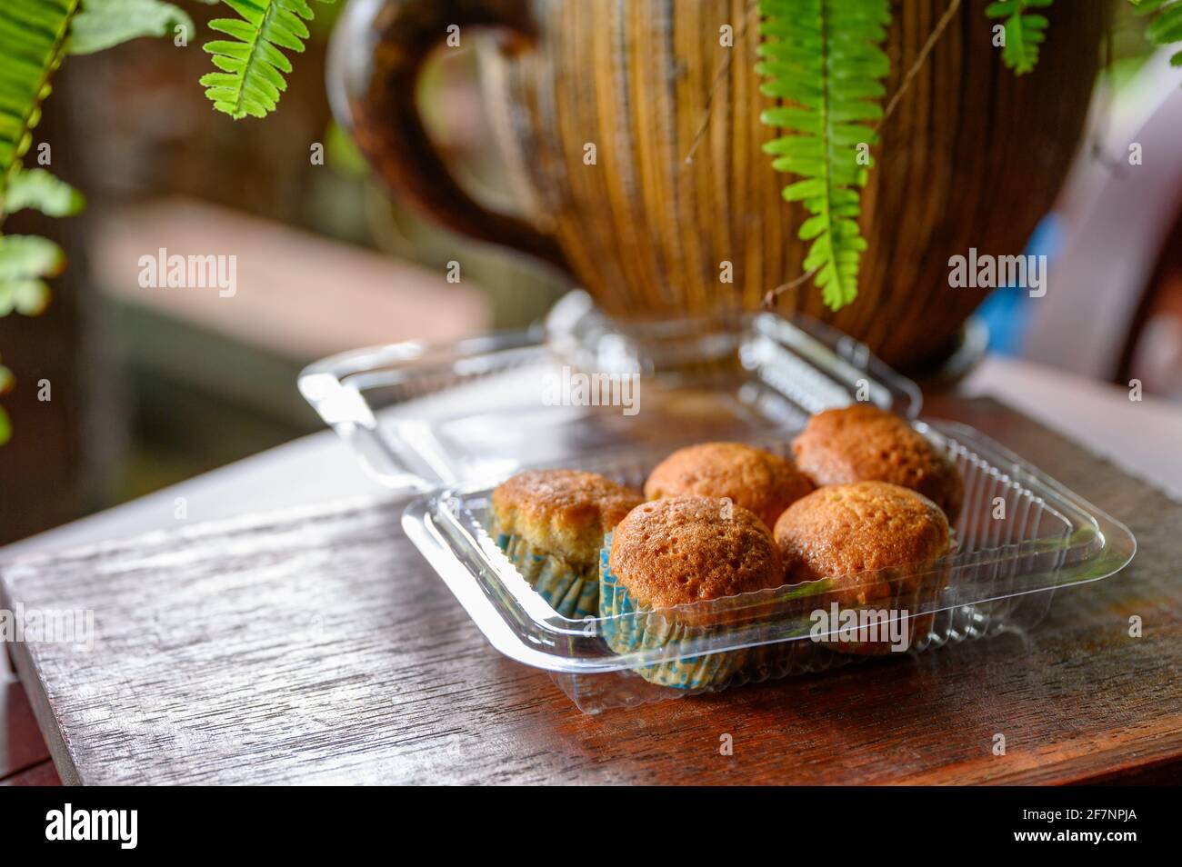 Muffin o cupcake al vapore alla banana cotta su scatola di plastica su tavolo di legno Foto Stock