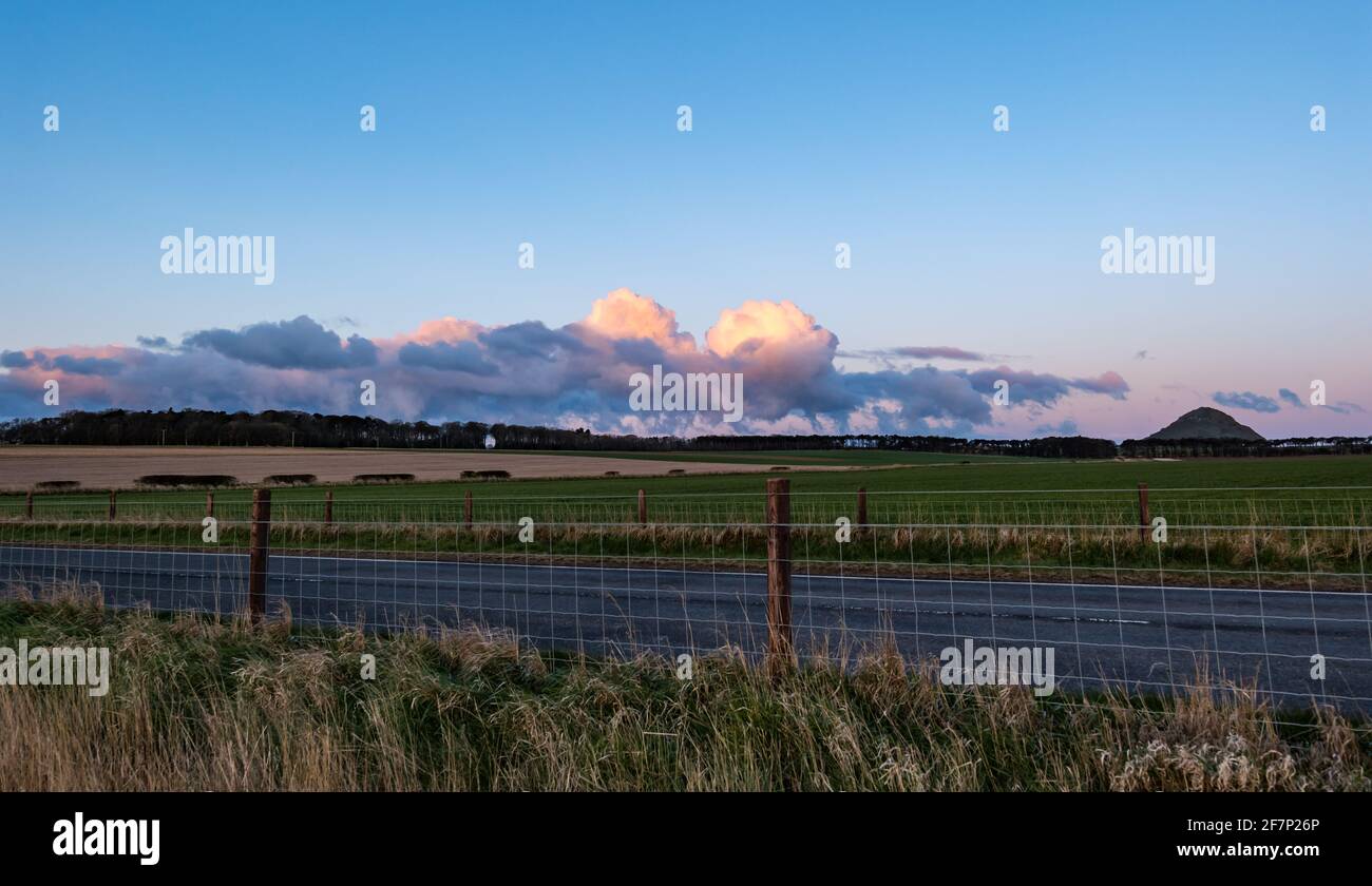 East Lothian, Scozia, Regno Unito. 9 Apr 2021. Regno Unito Meteo: alba. Mattina colore nelle nuvole rosa soffici con il profilo di Berwick Law collinetta vulcanica su una bella primavera fredda mattina Foto Stock