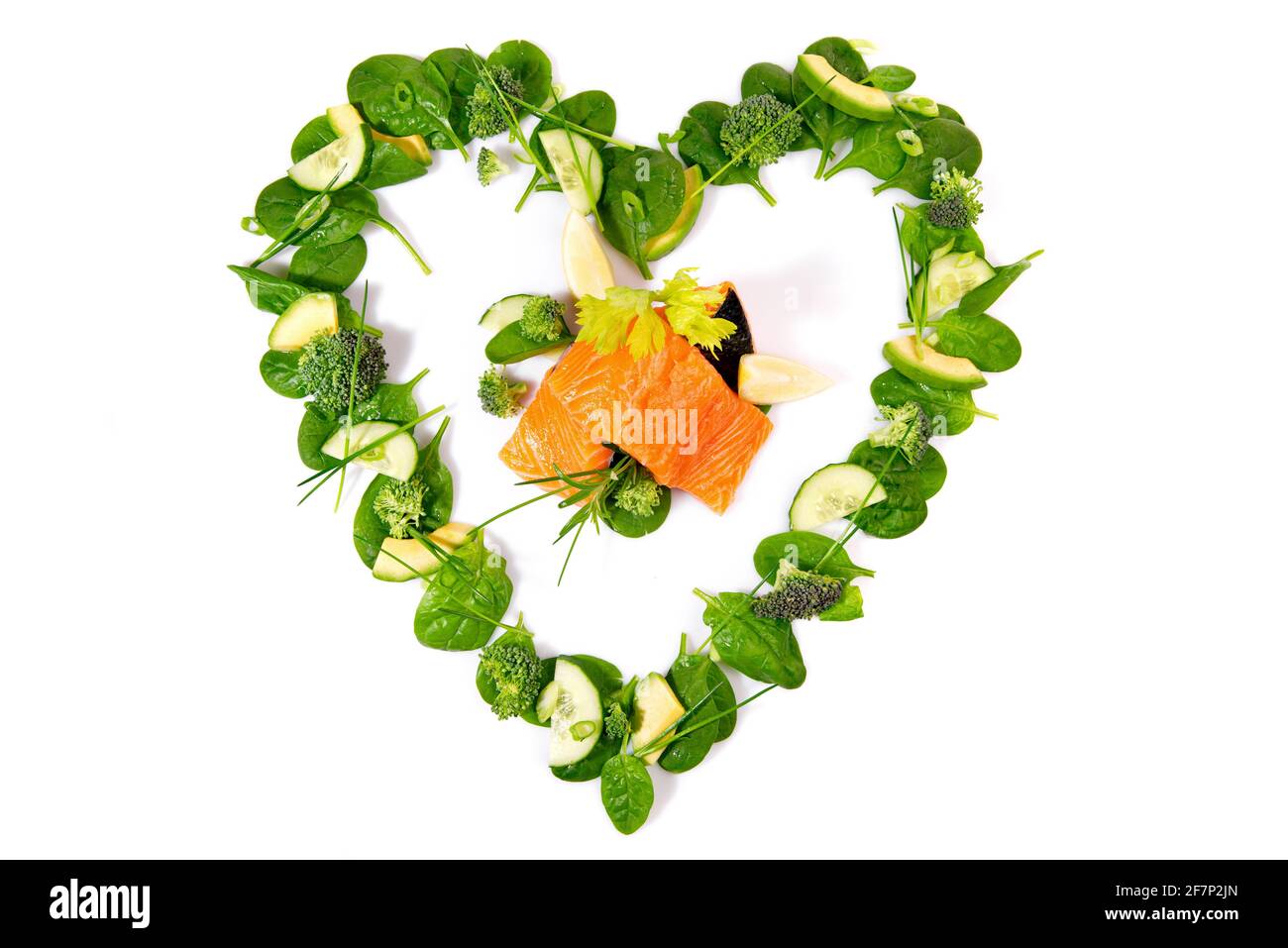 Insalata verde a forma di cuore e verdure con salmone grezzo isolato Su sfondo bianco Foto Stock