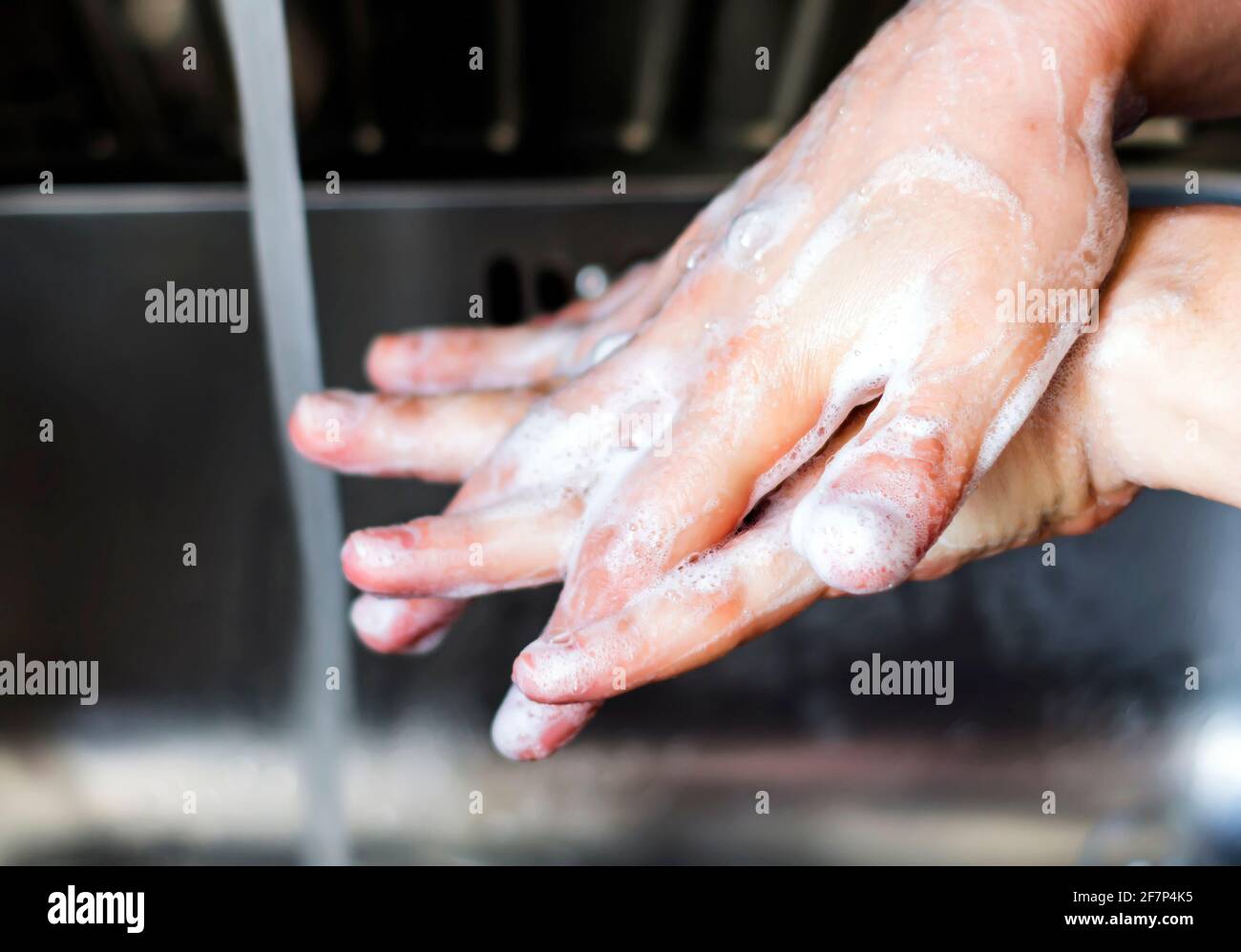 giovane donna caucasica che le lava le mani con sapone. Mano destra sopra la mano sinistra. Tenere le mani pulite. Cura personale Foto Stock